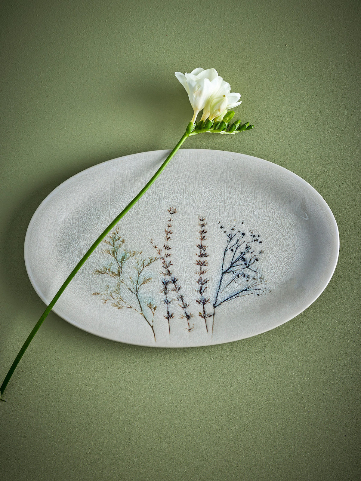 Weisse Servierplatte aus Steingut von Bloomingville mit handgestempeltem Blumenmuster und feiner Krakeleeglasur, länglich geformt.