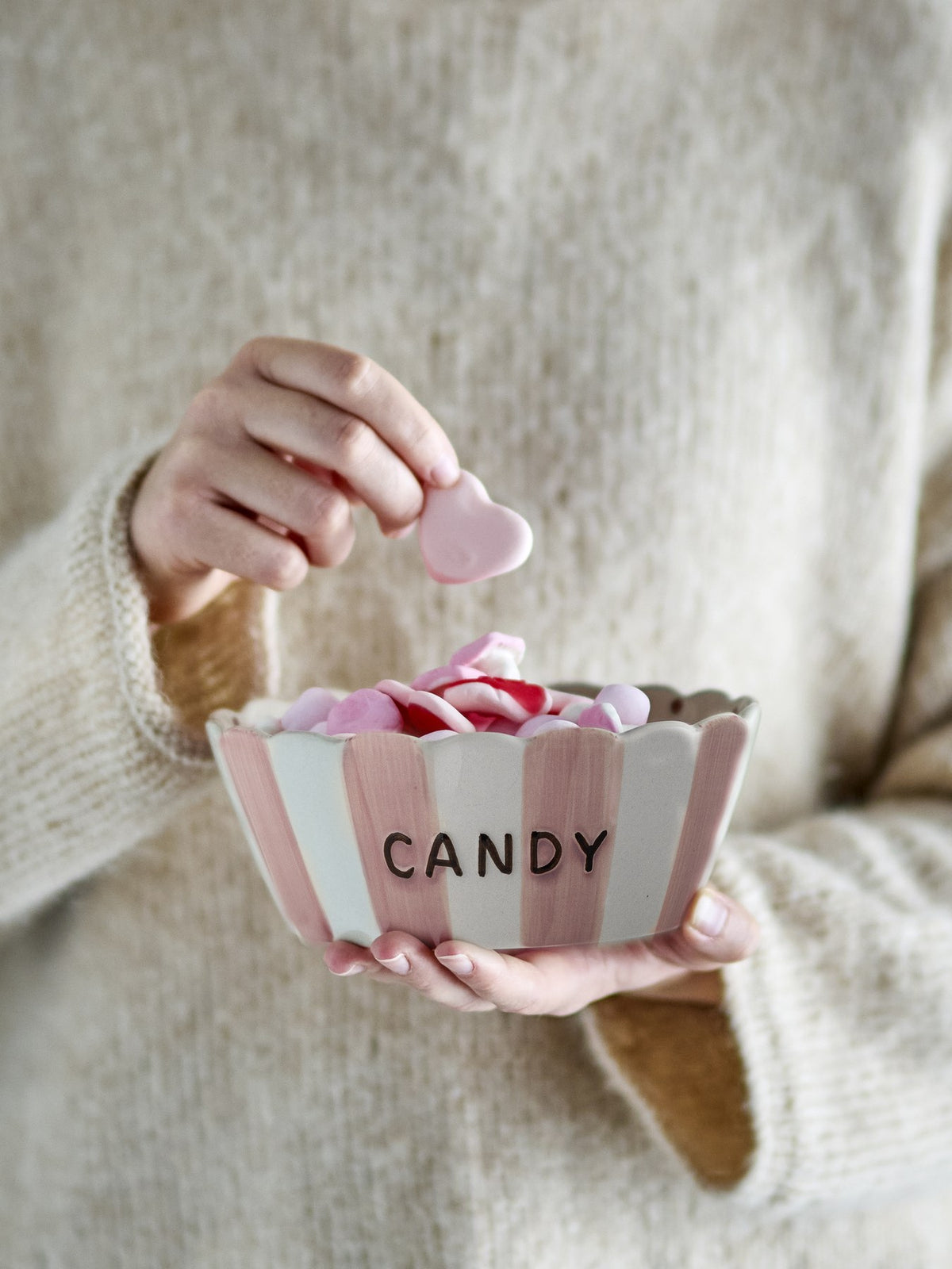 Rosafarbene Steingutschale mit gewelltem Rand, handbemalten vertikalen Streifen aussen und feinen Punkten innen, Schriftzug CANDY an der Seite.