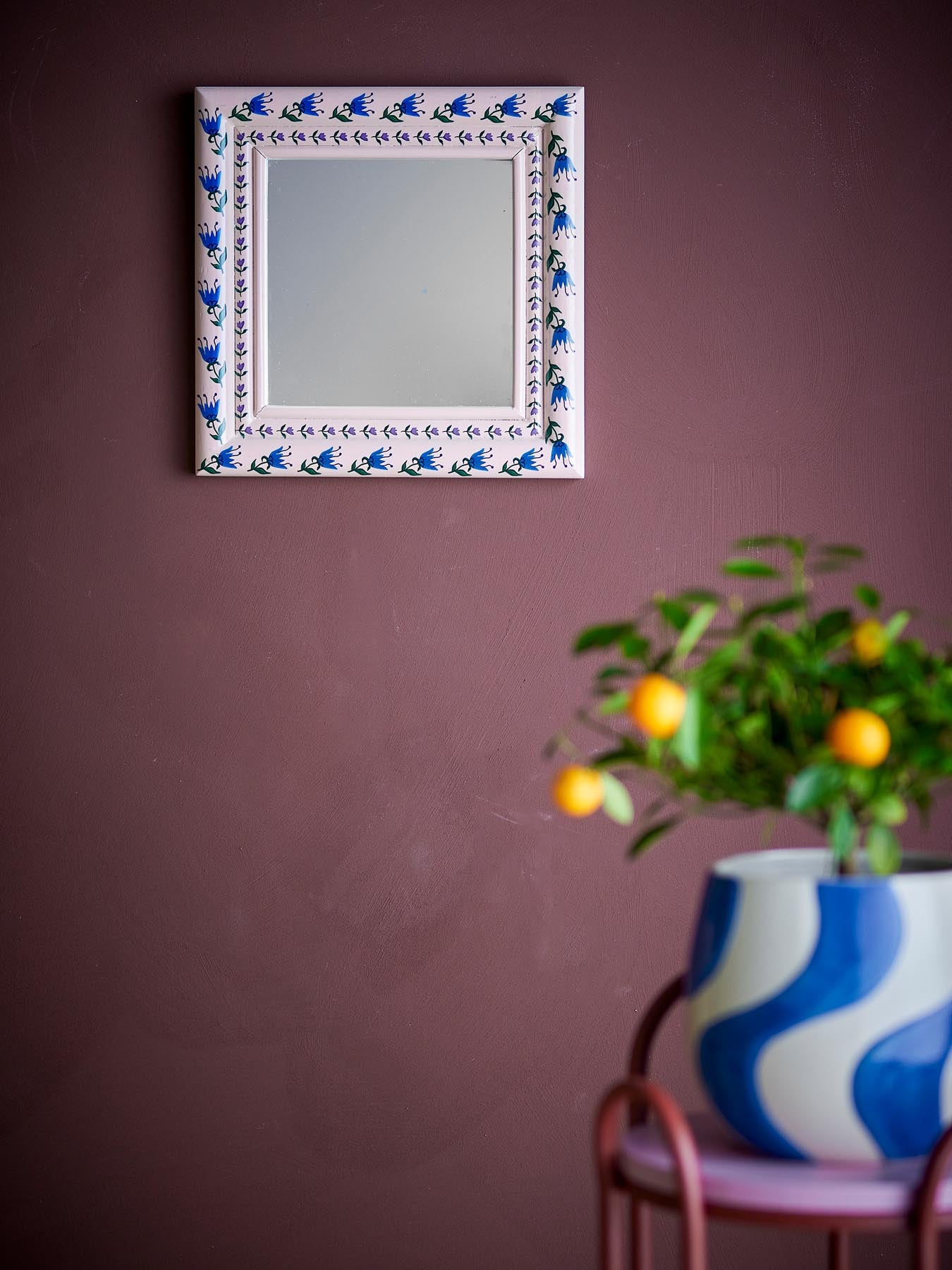 Entdecken Sie den Badia Wand-Spiegel von Bloomingville: Ein handbemalter Kiefernholzrahmen in zartem Rosé mit charmanten blauen Blumenakzenten.