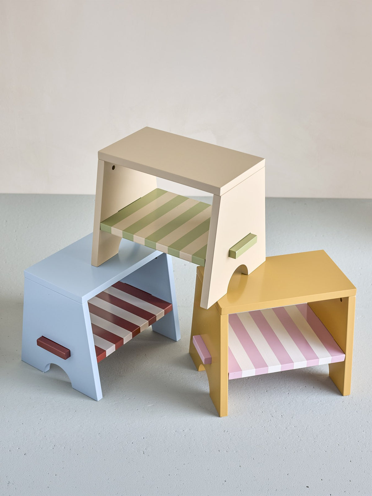 Liova Hocker von Bloomingville Mini aus lackiertem MDF, hellgelber Rahmen mit rosafarbenen Streifen auf der Sitzfläche, kleine Sitzgelegenheit.