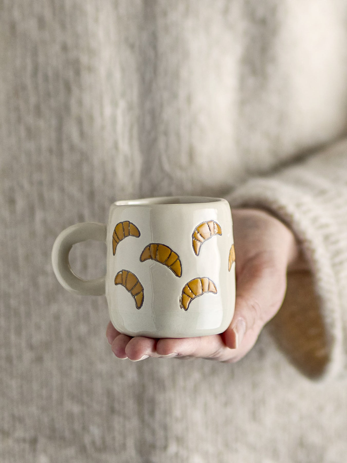 Millie Tasse von Bloomingville Mini aus Steingut, handbemalt mit Croissant-Motiven in Orange, Beige und Grün, kleine runde Form.