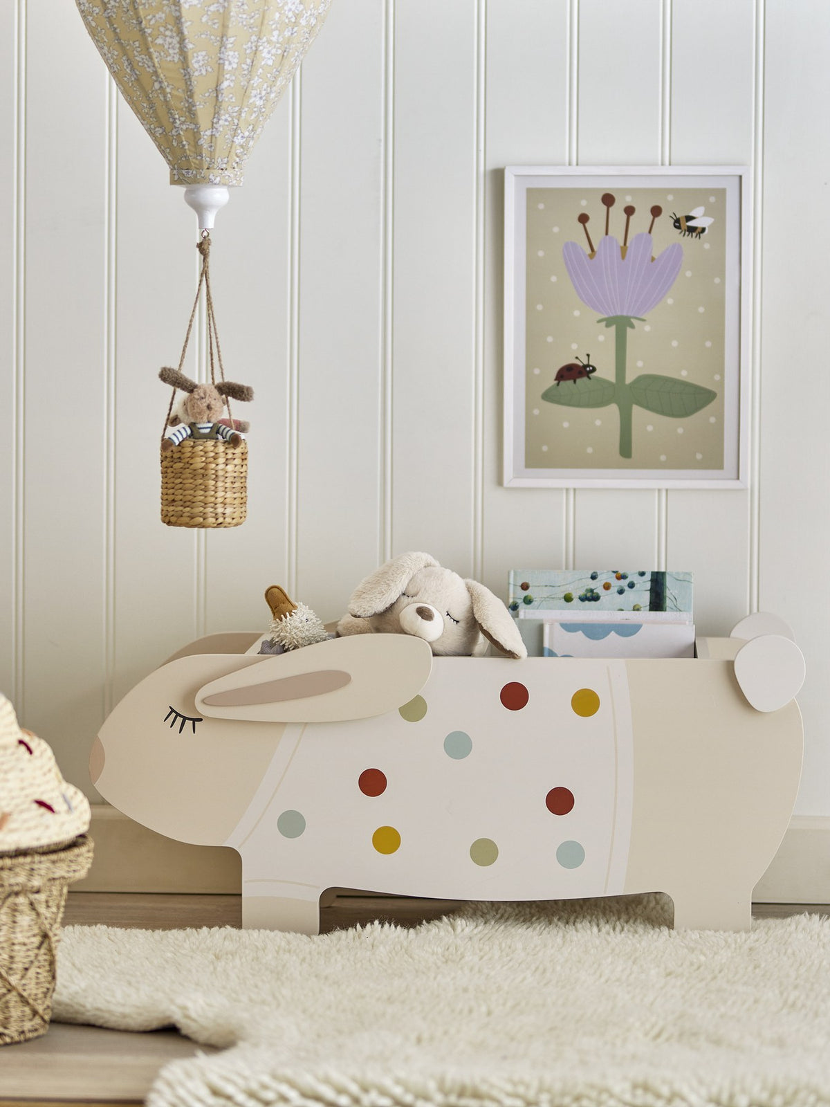 Buntes Bücherregal aus MDF in Kaninchenform mit weissen Beinen, offenes Fach für Bücher und Spielzeug im Kinderzimmer.