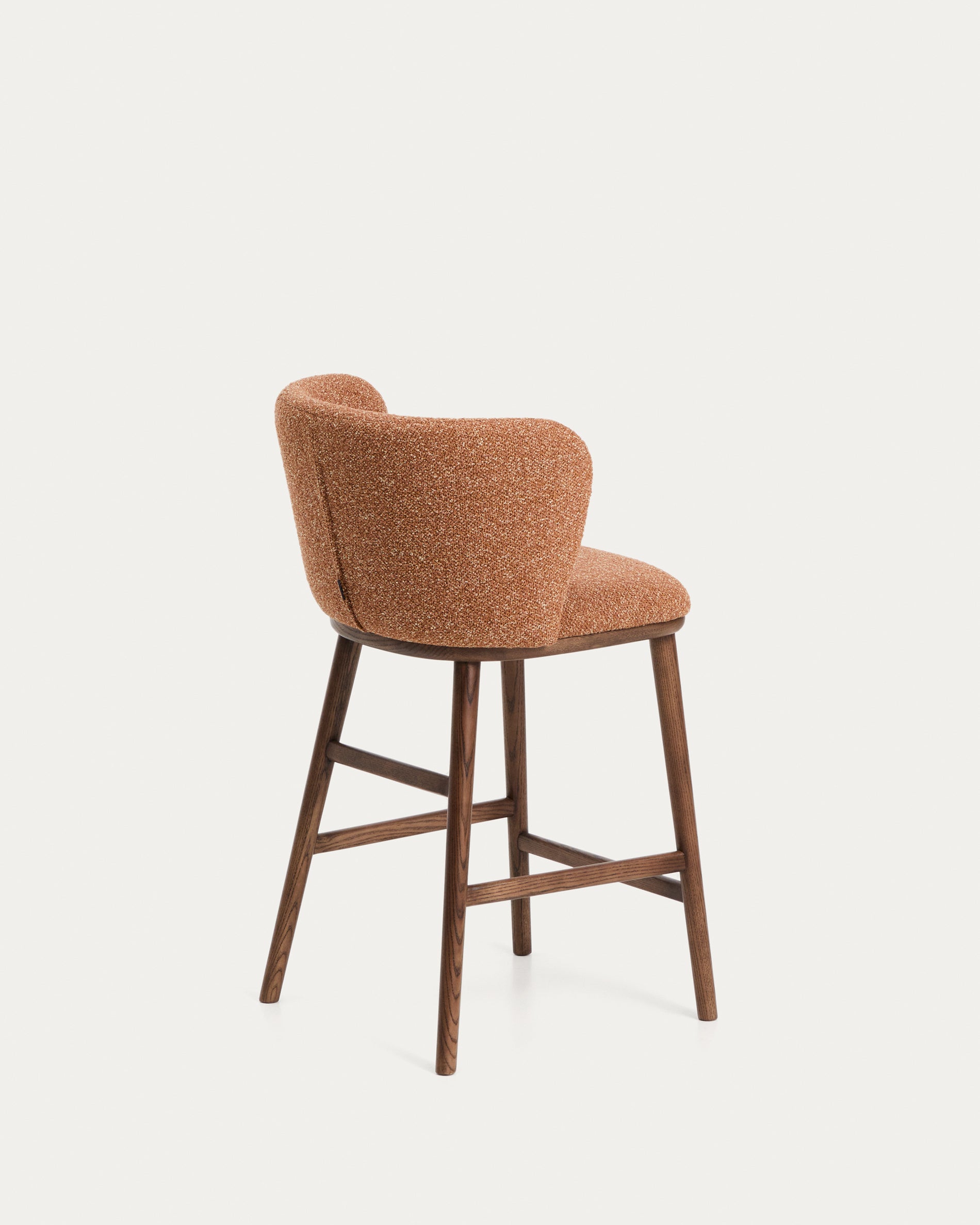 Stylischer Hocker Ciselia aus dickem terrakottafarbenem Chenille, mit robusten Eschenholzbeinen in edler Walnussfarbe, perfekt für moderne Wohnräume.