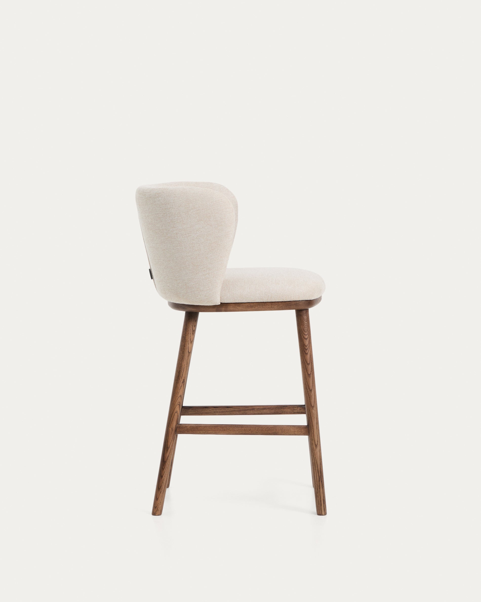 Eleganter Hocker Ciselia aus beigem Chenille, ausgestattet mit stabilen Eschenholzbeinen in edlem Walnussholz-Finish, ideal für stilvolle Bars.