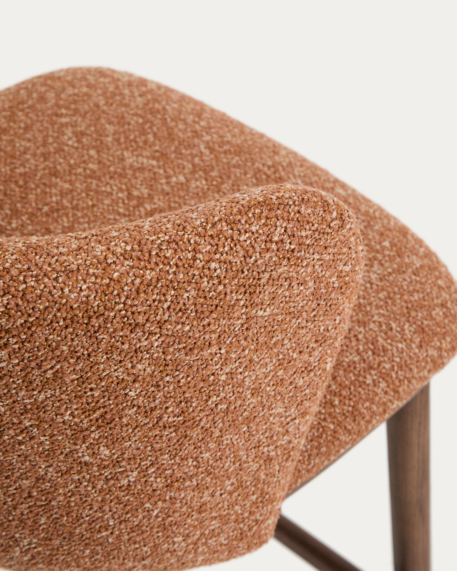 Stylischer Hocker Ciselia in warmem Terrakotta-Chenille, mit robusten Eschenholzbeinen in edler Walnussholz-Färbung, perfekt für moderne Barbereiche.