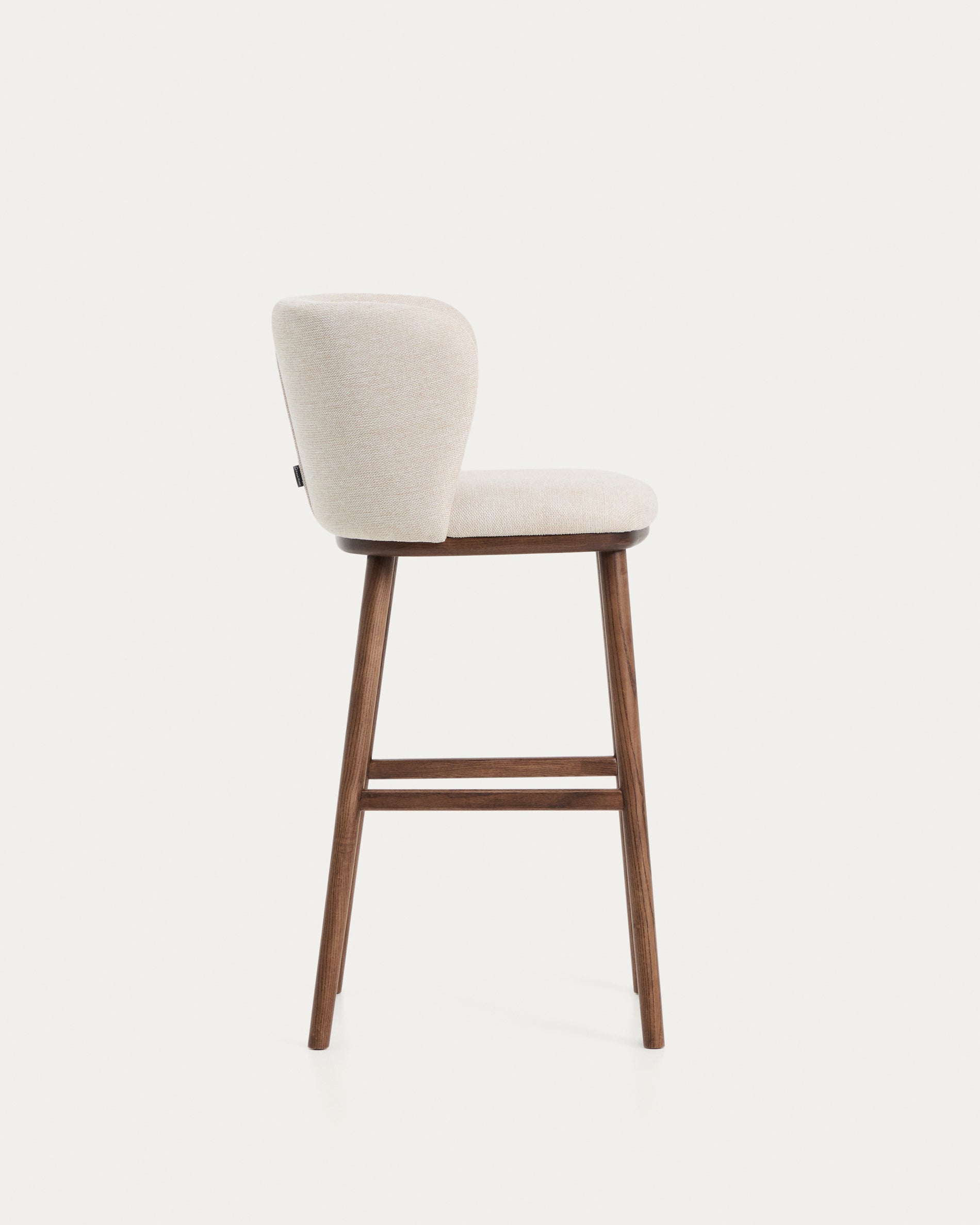 Eleganter Hocker Ciselia in beigem Chenille, ausgestattet mit stabilen Eschenholzbeinen in Walnussholzoptik, ideal für stilvolle Bar- und Wohnräume.