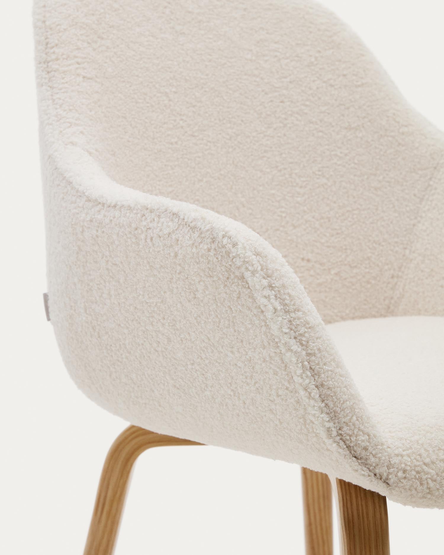 Eleganter Aleli Stuhl in strahlendem Weiß mit weichem Bouclé-Stoff und robusten Eschenholzbeinen. Ideal für stilvolle Wohnräume und Komfort.
