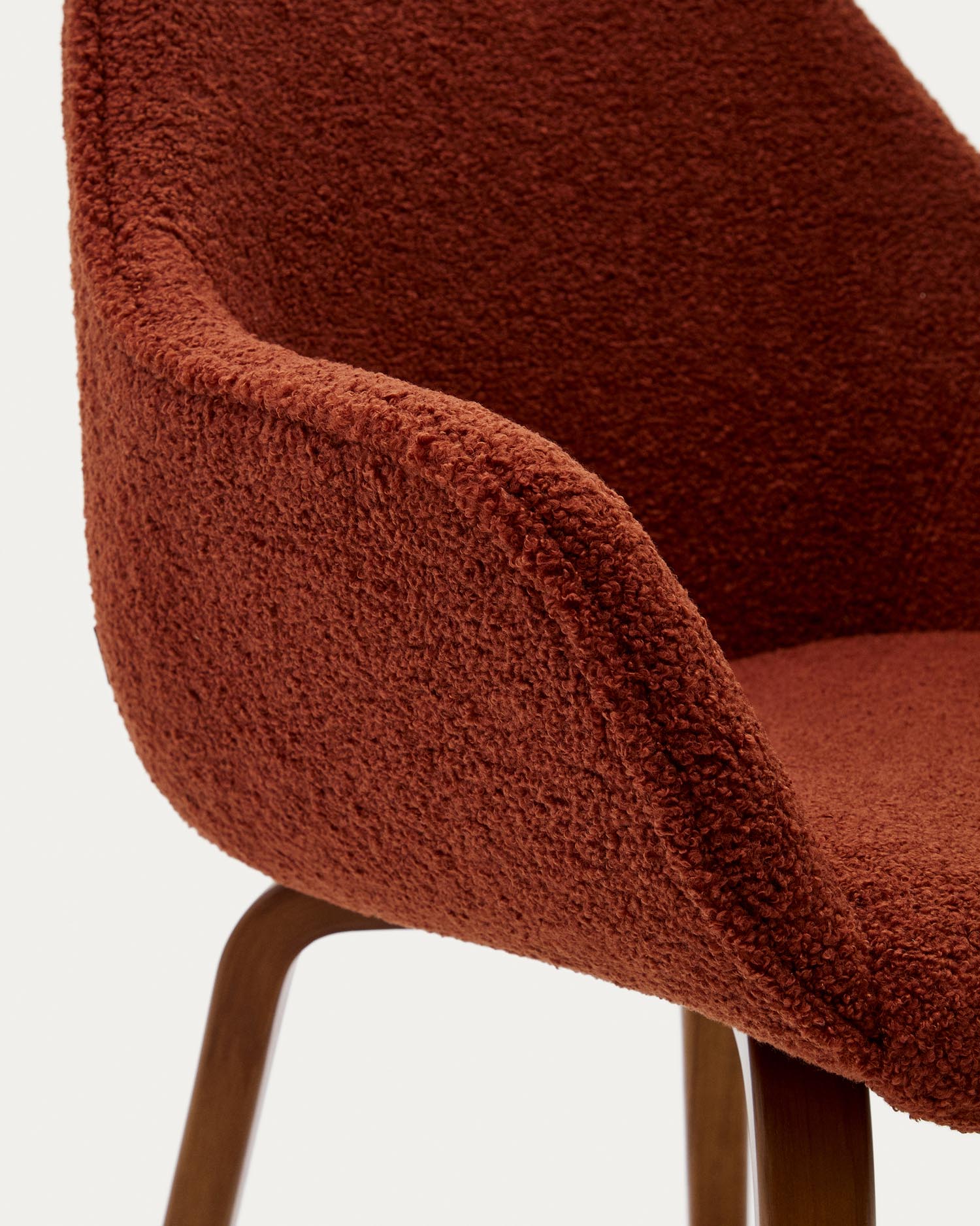 Eleganter Aleli Stuhl in warmem Terrakotta-Bouclé, ausgestattet mit stabilen Eschenholzbeinen und edlem Nussholz-Finish – ideal für stilvolle Wohnräume.