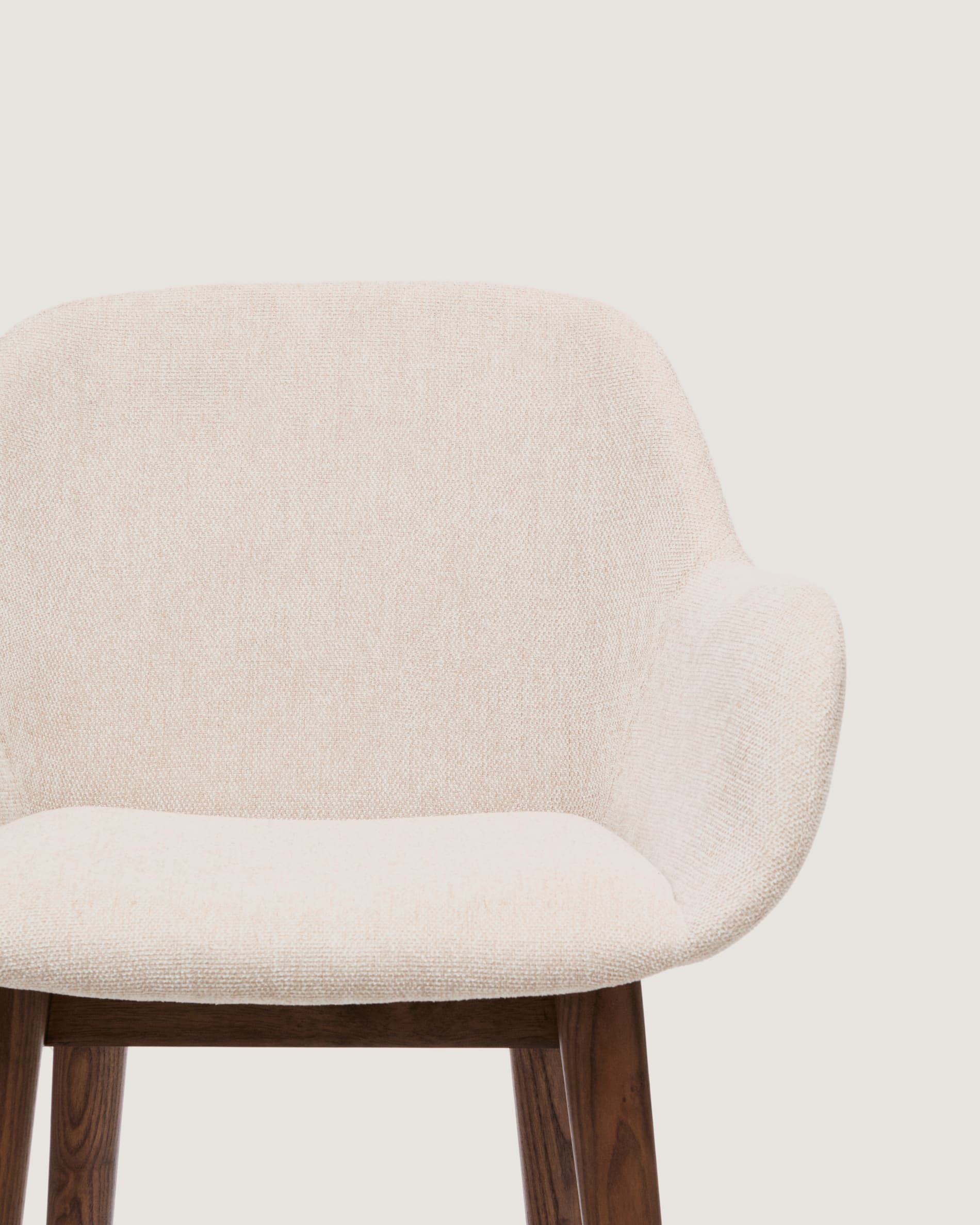 Eleganter Hocker Konna in Beige, 65 cm hoch, mit stabilen Eschenholzbeinen im dunklen Finish. Ideal für moderne Küchen und Essbereiche.