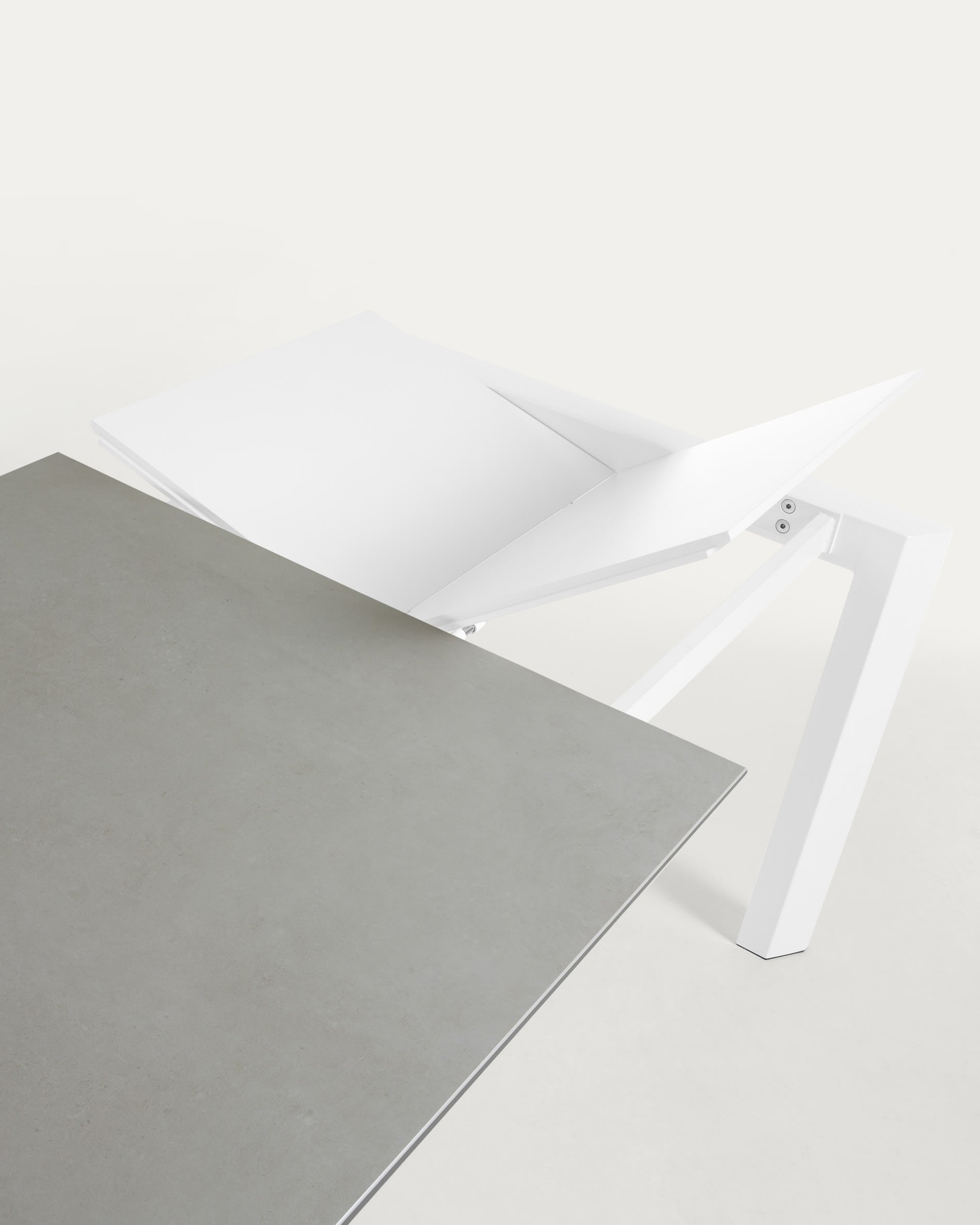 Moderner Ausziehtisch mit robuster Feinsteinzeugplatte in Hydra Plomo und stabilen weißen Stahlbeinen, flexibel von 120 auf 180 cm erweiterbar.