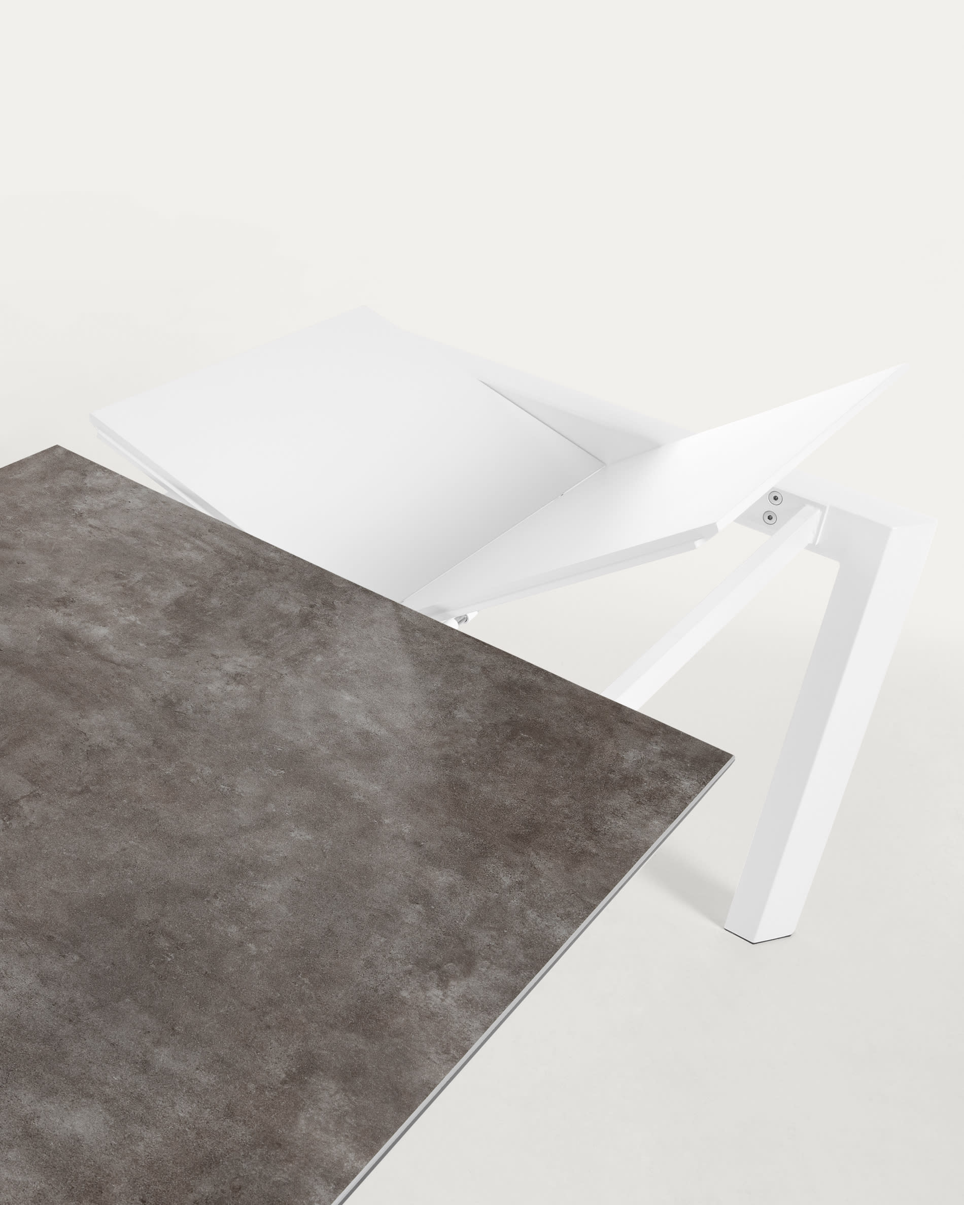 Eleganter Ausziehtisch mit robuster Feinsteinzeugplatte in stilvollem Vulcano Ceniza Finish und stabilen, weißen Stahlbeinen, erweiterbar von 120 auf 180 cm.