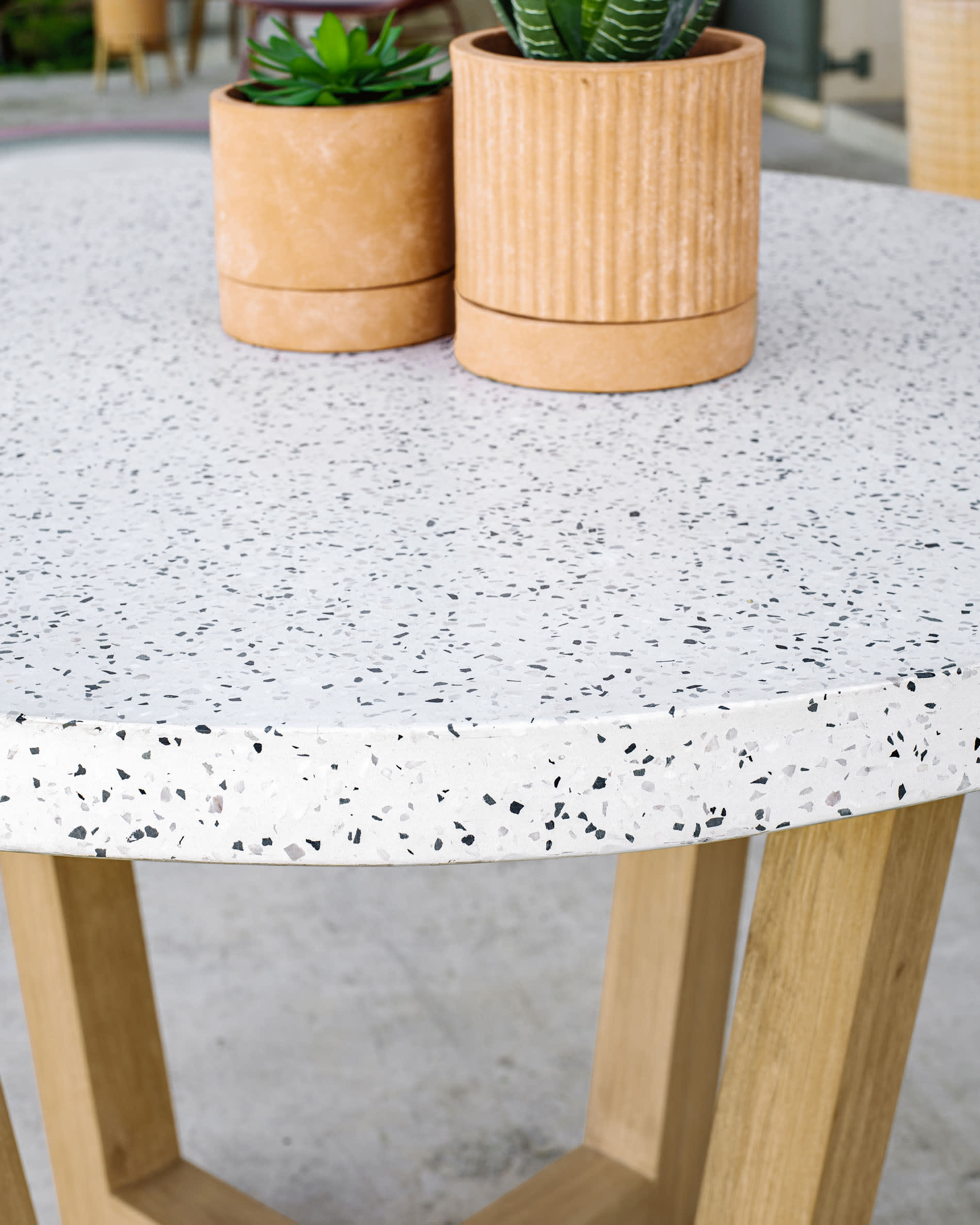 Moderner runder Tisch mit weißer Terrazzo-Platte und Akazienholzgestell, Ø 120 cm, ideal für stilvolle Essbereiche, von Kave Home.