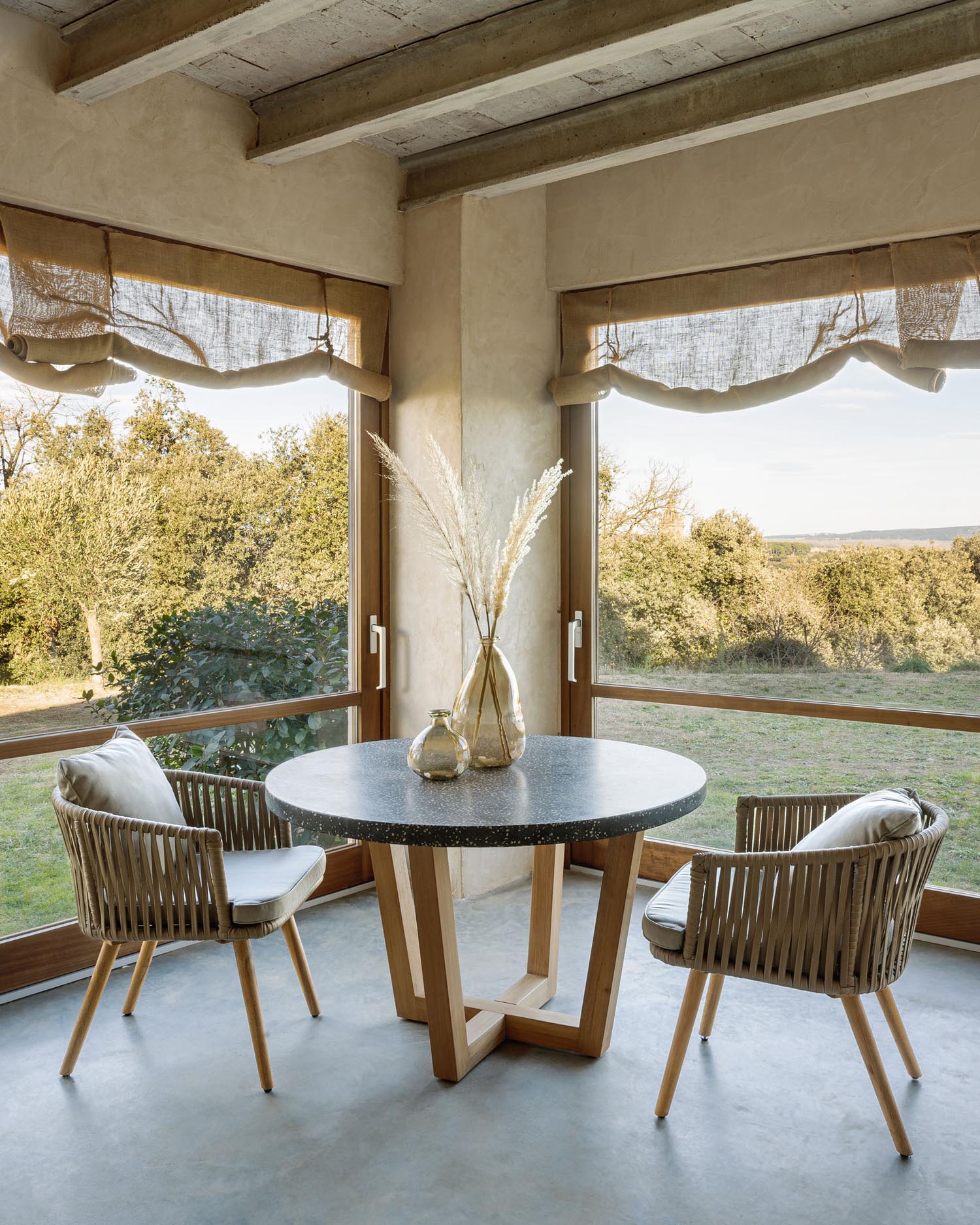 Entdecken Sie den Shanelle runden Tisch von Kave Home: 120 cm Durchmesser, edle Terrazzo-Oberfläche und robustes Akazienholz für Ihren Garten.