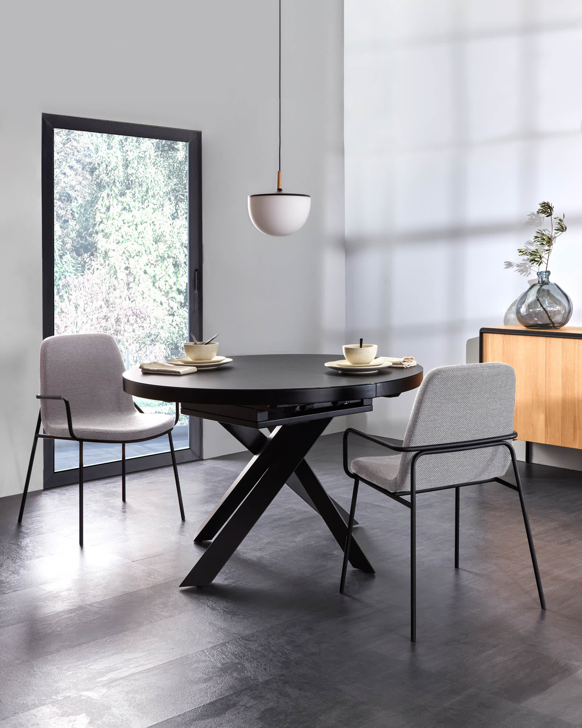 Eleganter runder Ausziehtisch mit Glasplatte und schwarzen Stahlbeinen, Ø 120-160 cm, perfekt für moderne Wohnräume.