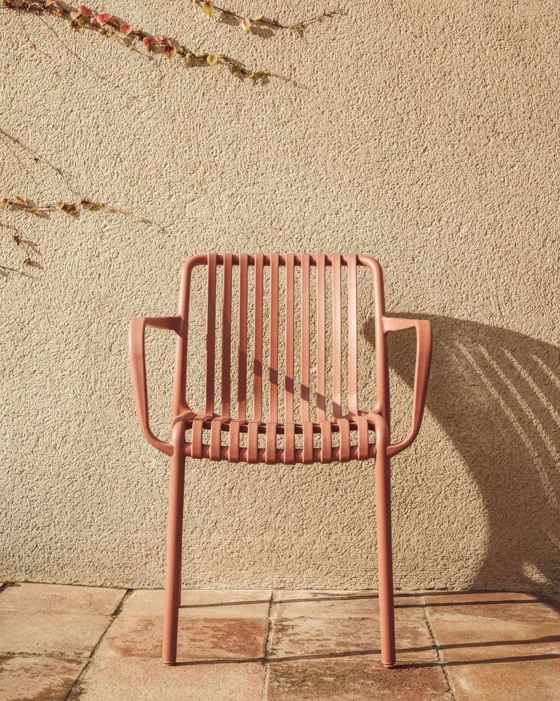 Eleganter stapelbarer Gartenstuhl Isabellini in warmem Terrakotta, ideal für stilvolle Outdoor-Bereiche und entspannte Stunden im Freien.