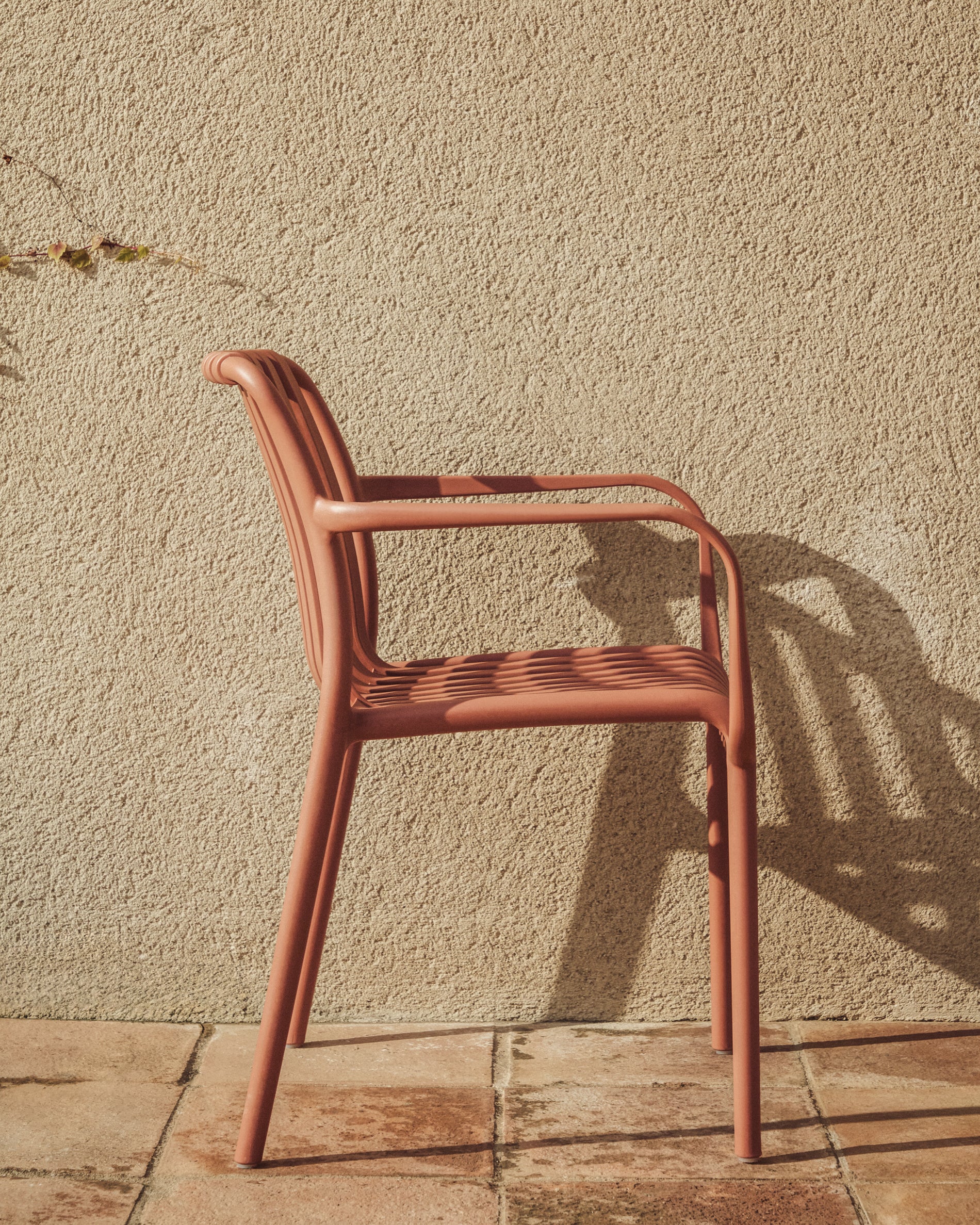 Eleganter stapelbarer Gartenstuhl Isabellini in warmem Terrakotta, ideal für stilvolle Outdoor-Bereiche und gesellige Stunden im Freien.