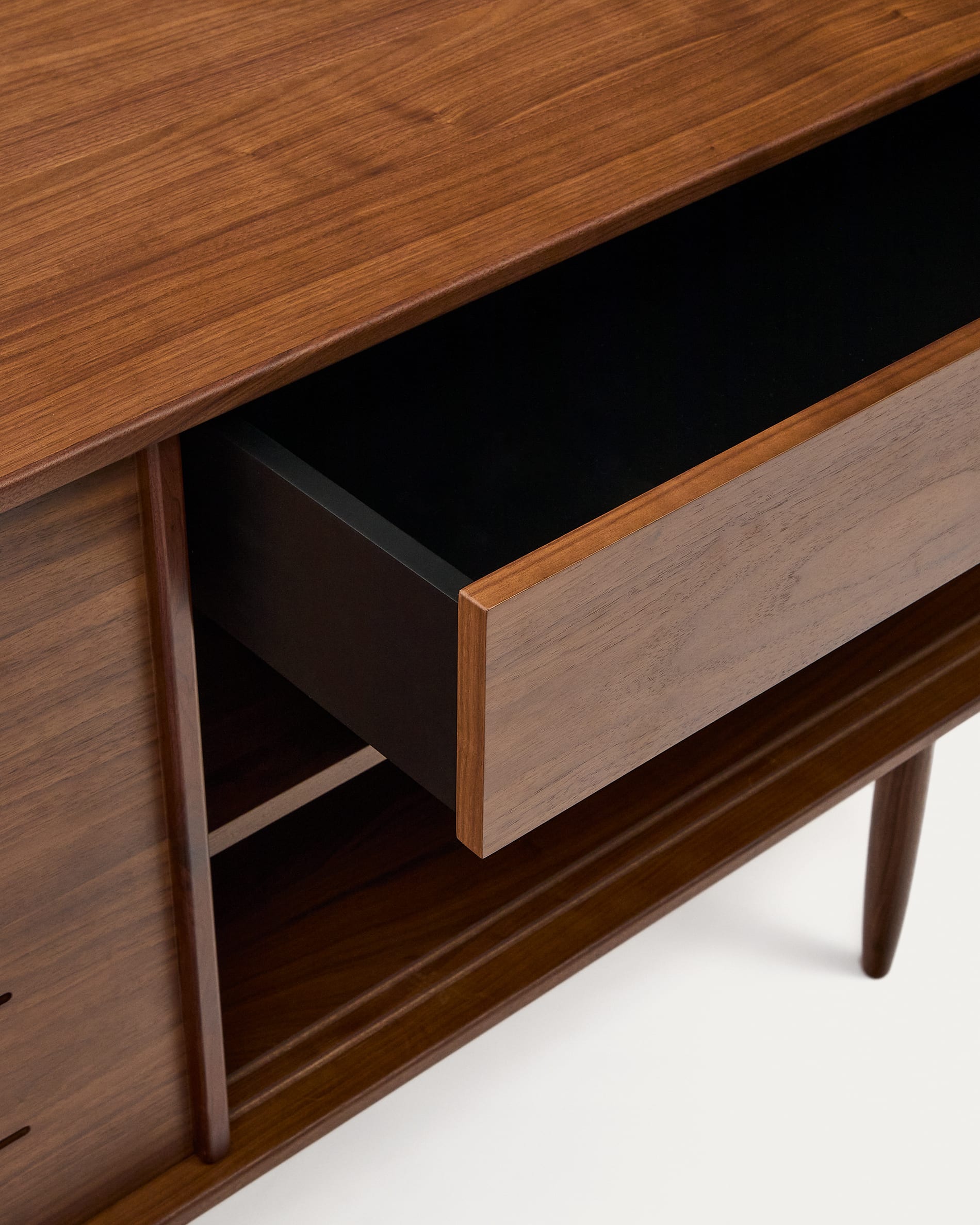 Das Carolin Sideboard von Kave Home vereint 50er Jahre Eleganz mit modernem Design. Aus Nussholzfurnier gefertigt, bietet es großzügigen Stauraum.