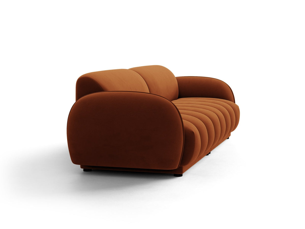Vierersofa Bilbao mit hellbeigem Samtbezug, schwarzen Kunststoffbeinen und klarer, gerader Linienführung, fotografiert freistehend im Raum.