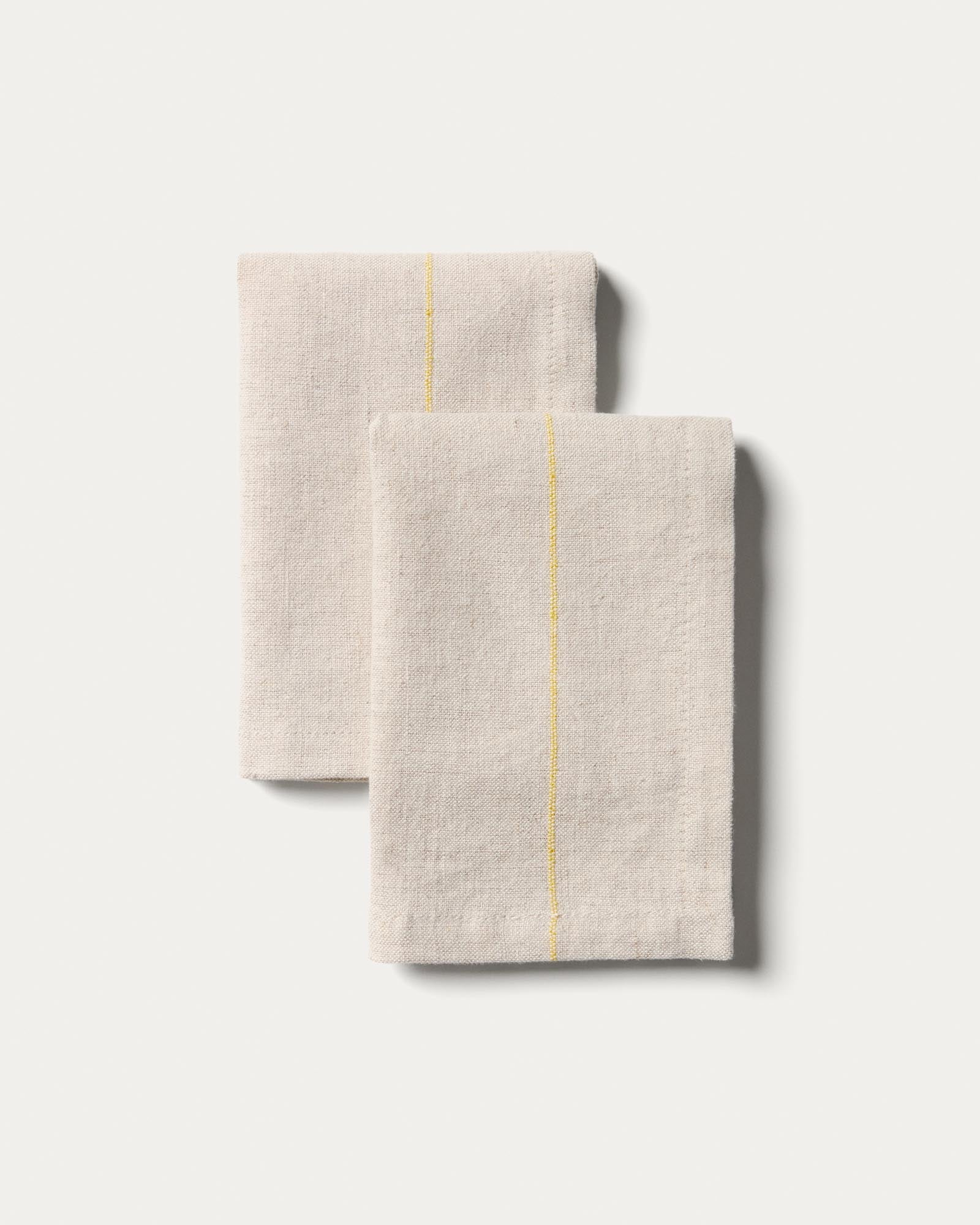 Elegantes Set Ulaen mit zwei Servietten (35 x 35 cm) aus hochwertiger Baumwolle und Leinen in sanftem Beige, verziert mit lebhaften gelben Streifen.