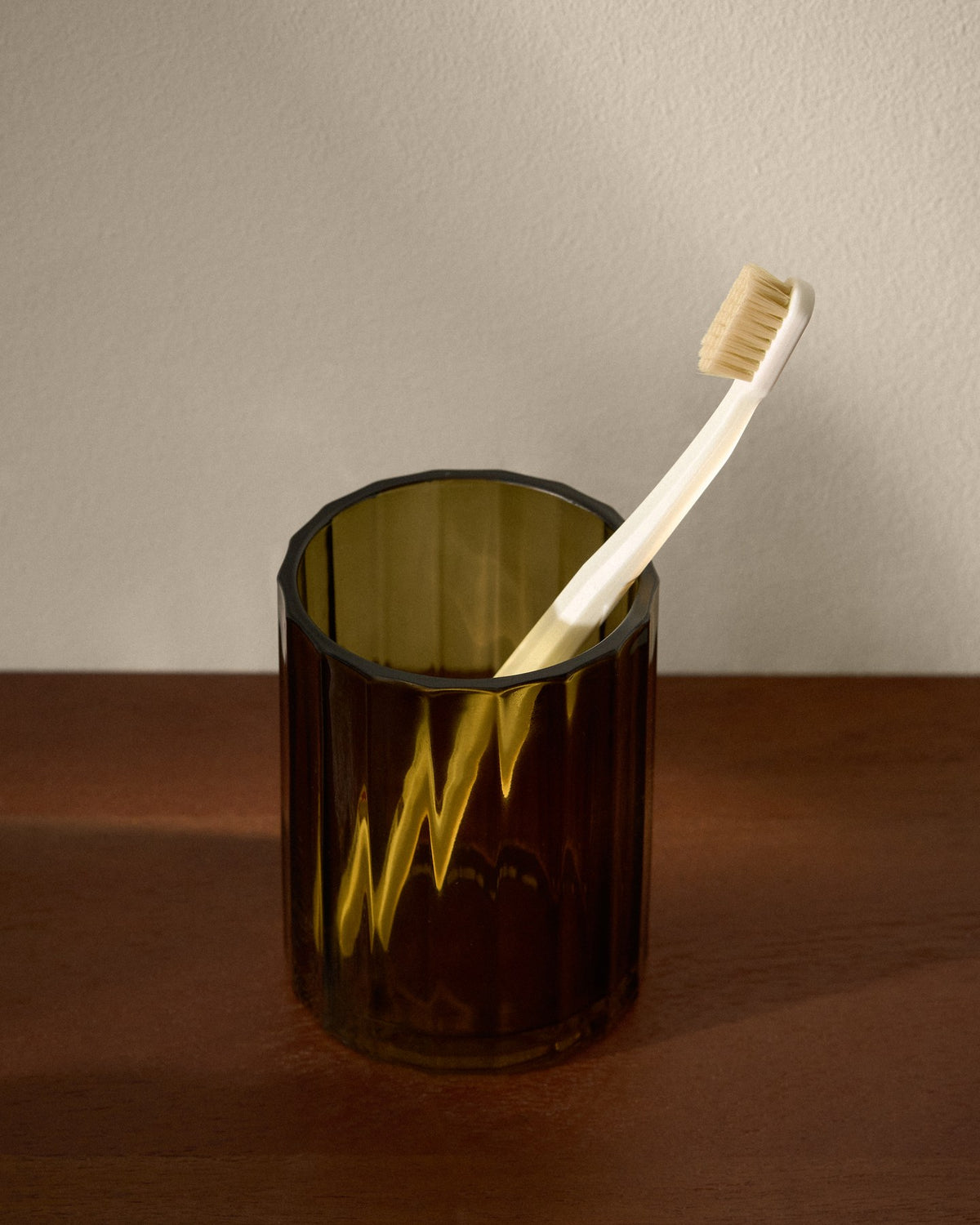 Runder Zahnbürstenhalter aus grünem Glas mit farbiger Oberfläche, Durchmesser 11 cm, Höhe 2 cm, auf hellem Untergrund fotografiert.