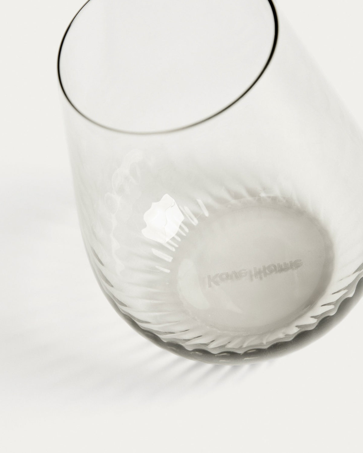 Hellgraues Trinkglas aus 100% Glas mit abgerundeter Basis und grauem Boden, klare Oberfläche, kompakte Form für Getränke.