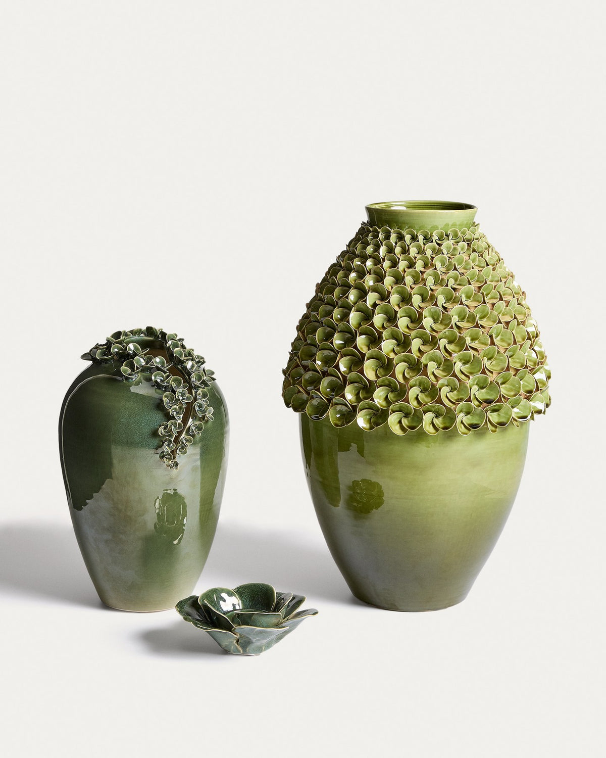 Hellgrüne Keramikvase Ederia von Kave Home mit floralen, handgeformten Blütenelementen, glasierter Oberfläche und rundlicher Form.