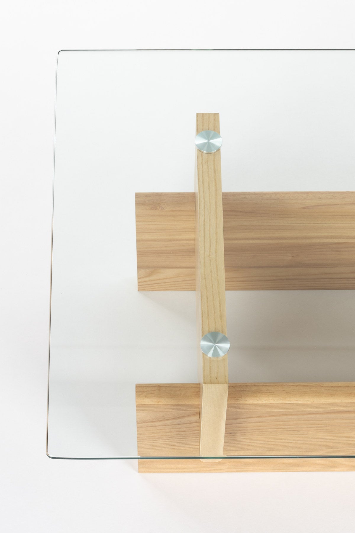 Couchtisch Lucifer Natural von Dutchbone mit Gestell aus zwei quer angeordneten Holzplatten und rechteckiger Tischplatte aus transparentem Glas.