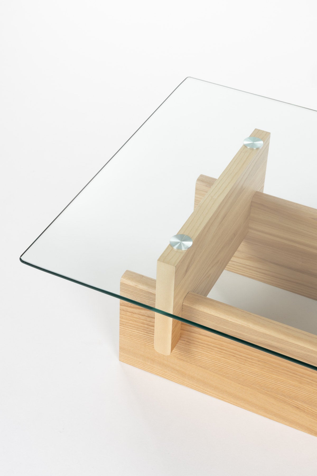Couchtisch Lucifer Natural von Dutchbone mit Gestell aus zwei quer angeordneten Holzplatten und rechteckiger Tischplatte aus transparentem Glas.