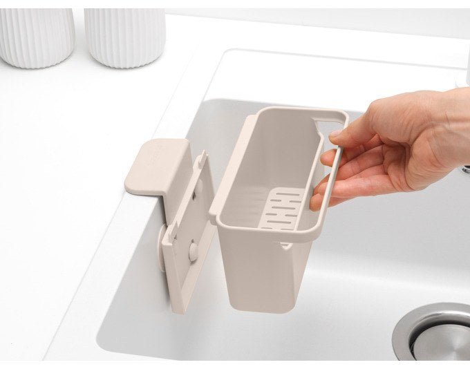 Hängender Spüleinsatz SinkSide von BRABANTIA in soft beige und weiss, montiert im Spülbecken mit Ablage für Schwamm und Lappen.