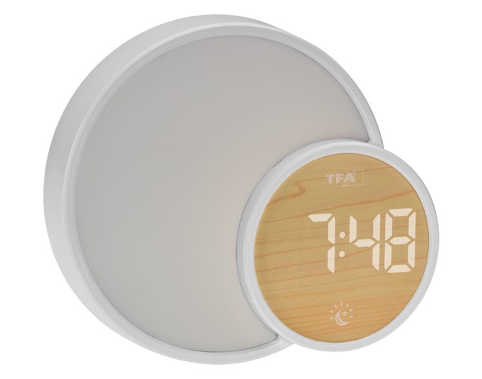 Weisser TFA Lichtwecker Soluna Mini mit rundem Gehäuse, LCD-Display, Farblicht-Ring und seitlichem USB-Anschluss auf einem Nachttisch.