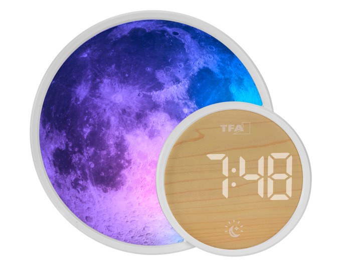 Weisser TFA Lichtwecker Soluna Mini mit rundem Gehäuse, LCD-Display, Farblicht-Ring und seitlichem USB-Anschluss auf einem Nachttisch.