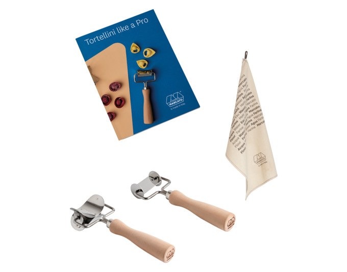 Silbernes Pasta-Ausstecher-Set von MARCATO mit quadratischer und runder Form, Rezeptheft und braunem Küchentuch auf hellem Untergrund.