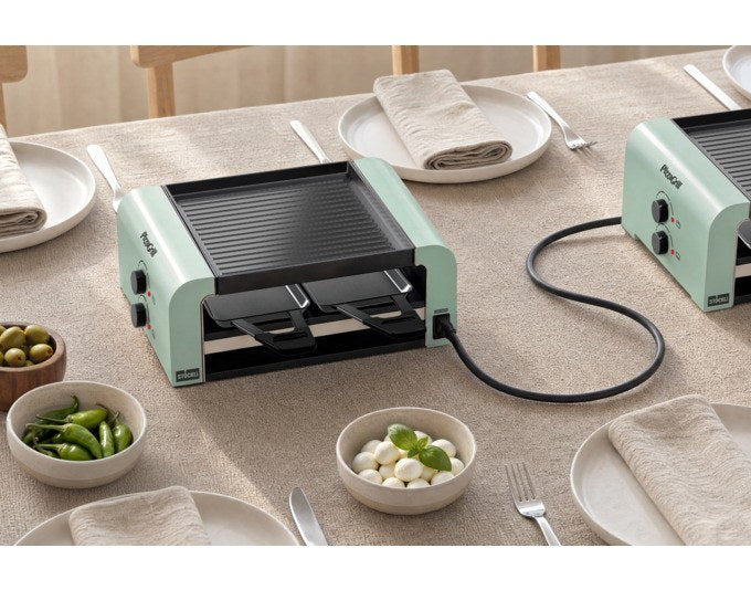 Tischgrill STÖCKLI PizzaGrill 4 Connect in mint green mit vier Pfännchen, Wende-Grillplatte und Teigausstecher auf hellem Hintergrund.