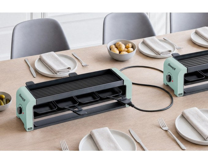 Mint grüner STÖCKLI CheeseGrill 4 Connect mit vier antihaftbeschichteten Pfännchen und wendbarer Aluguss-Grillplatte auf hellem Hintergrund.