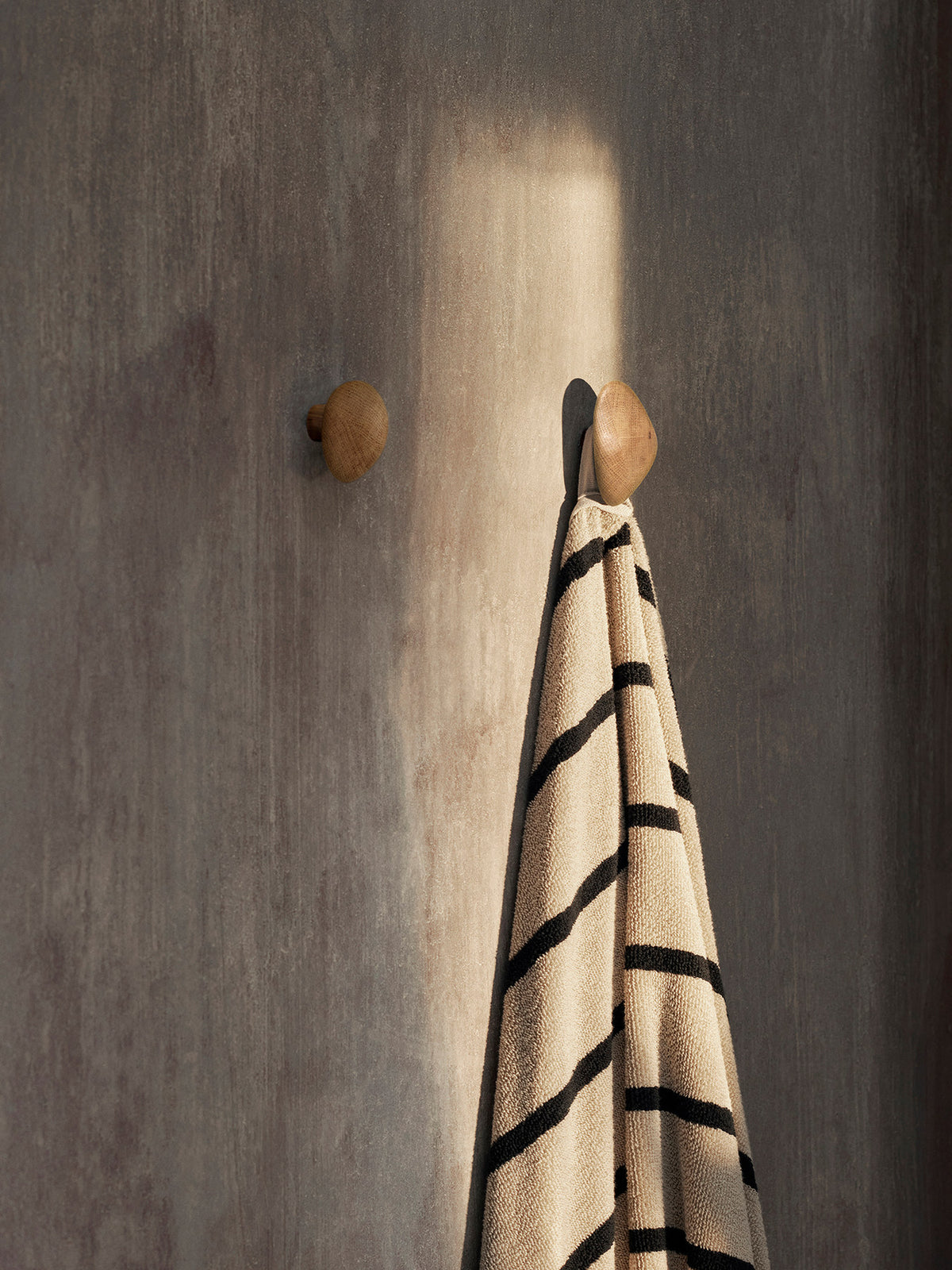 Zwei dunkelbraune Cairn Kleiderhaken aus FSC-zertifiziertem Eschenholz mit karbonisierter Oberfläche und abgerundeten, skulpturalen Formen von Ferm Living