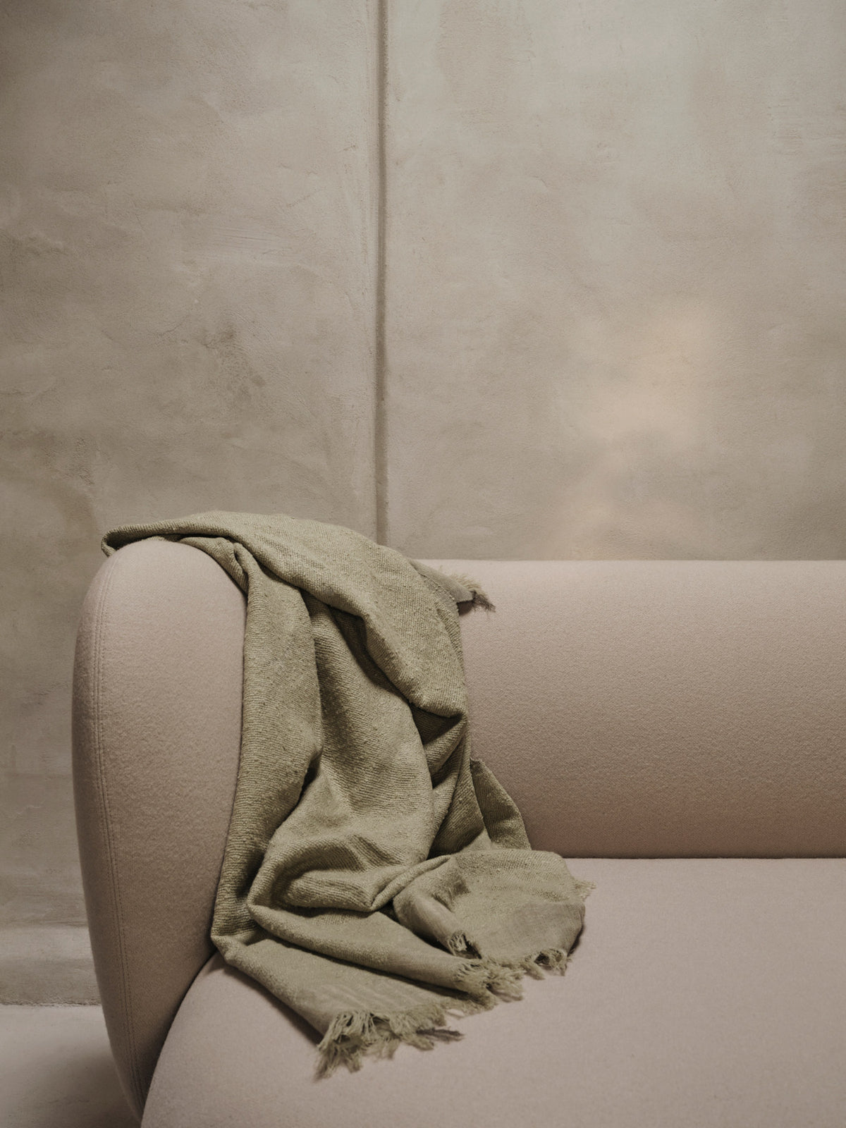 Weaver Throw Decke von Ferm Living, handgewebt aus Baumwolle, Merinowolle und Leinen, Farbe Avocado, mit feinen Fransen am Rand.