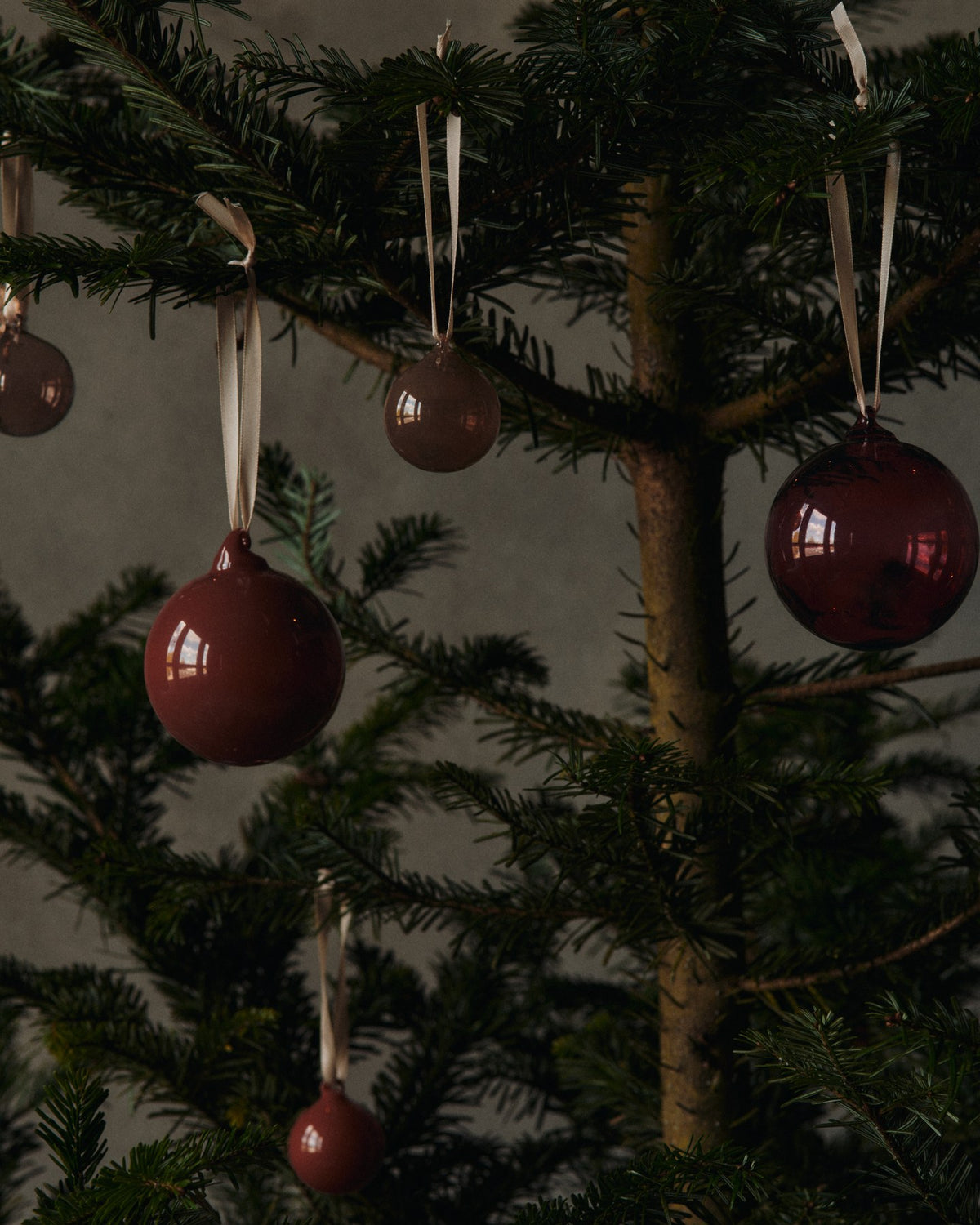 Drei kleine Glaskugeln in Rosenfarbig Opak aus mundgeblasenem Glas, mit cremefarbenem Polyesterband zum Aufhängen, als Weihnachtsornament.