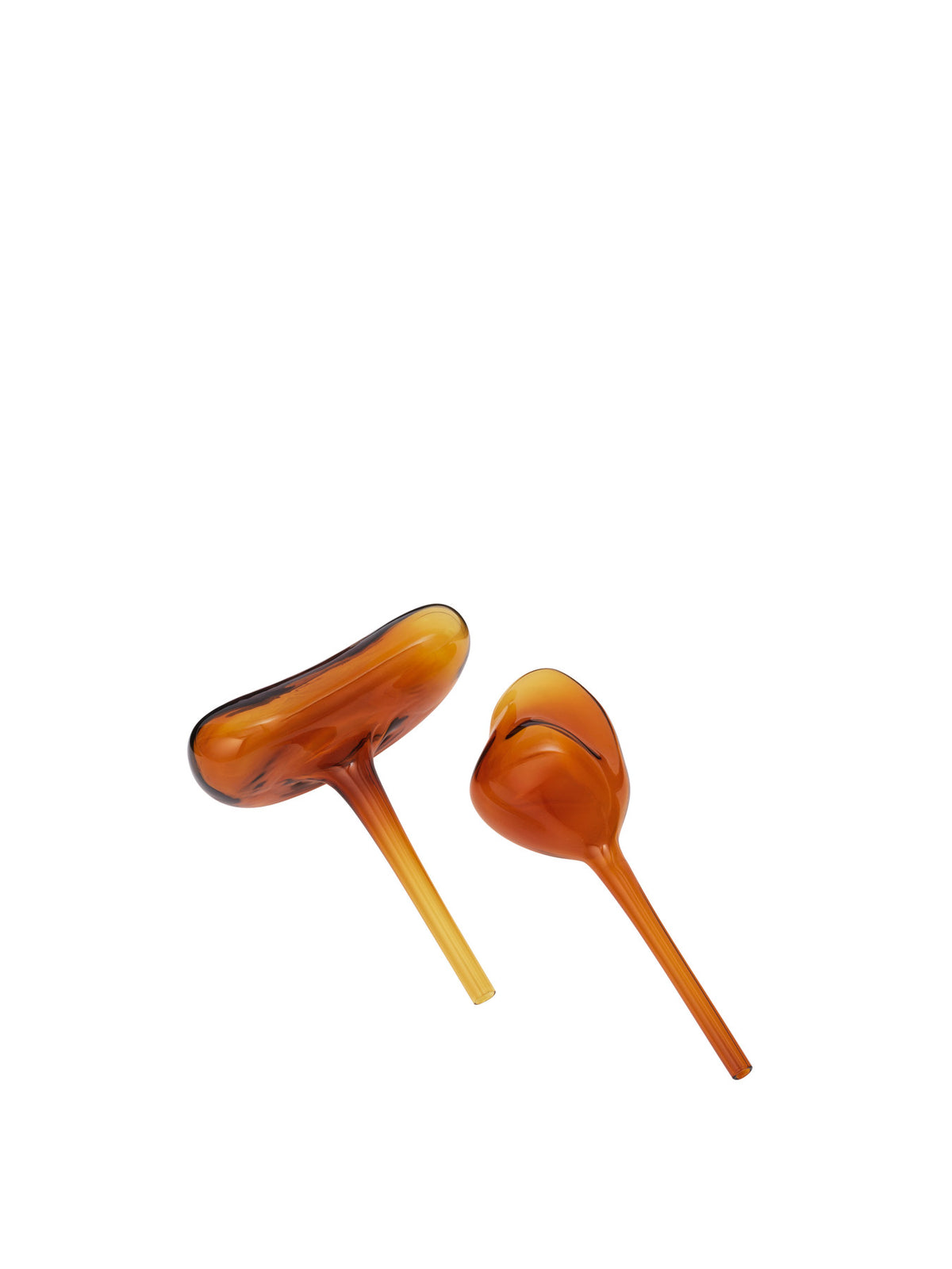 Zwei Wasserkugeln aus mundgeblasenem Glas in Amber von Ferm Living, organische Kugelform mit langem Stiel, stehend neben einem Pflanzentopf.
