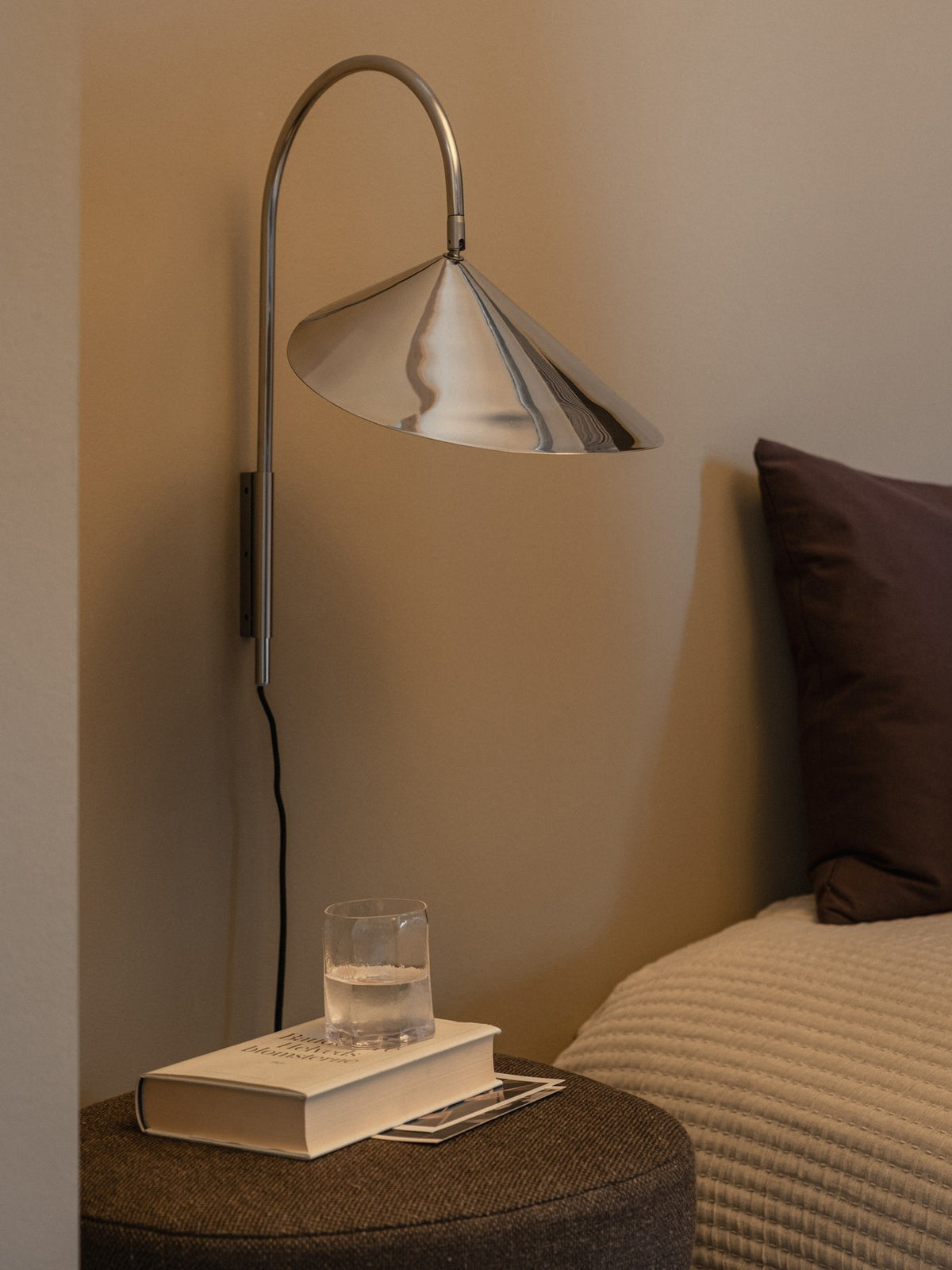 Arum Swivel Wandleuchte von Ferm Living in Edelstahl mit organisch geformtem Lampenschirm, schwenkbarem Arm und Textilkabel mit Schalter.