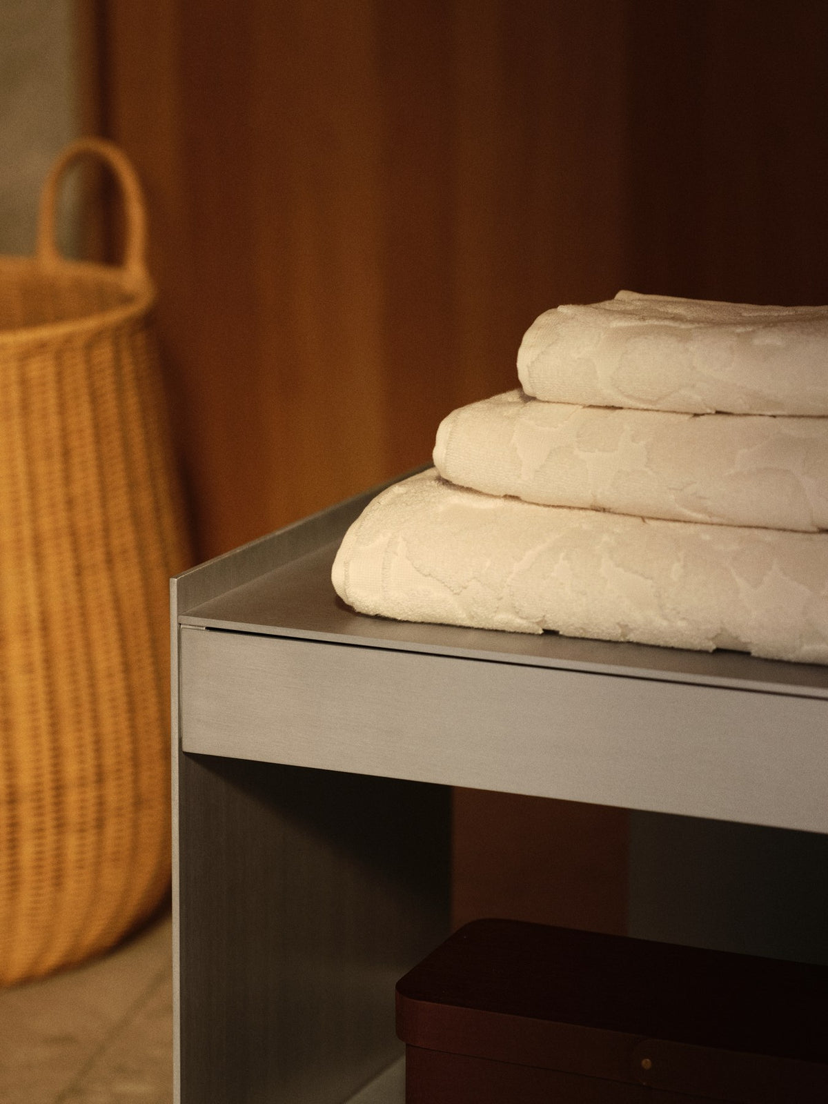 Off-white Badetuch aus Bio-Baumwolle mit sanftem, tonalem Blumenmuster, gefaltet auf hellem Untergrund, Ferm Living.
