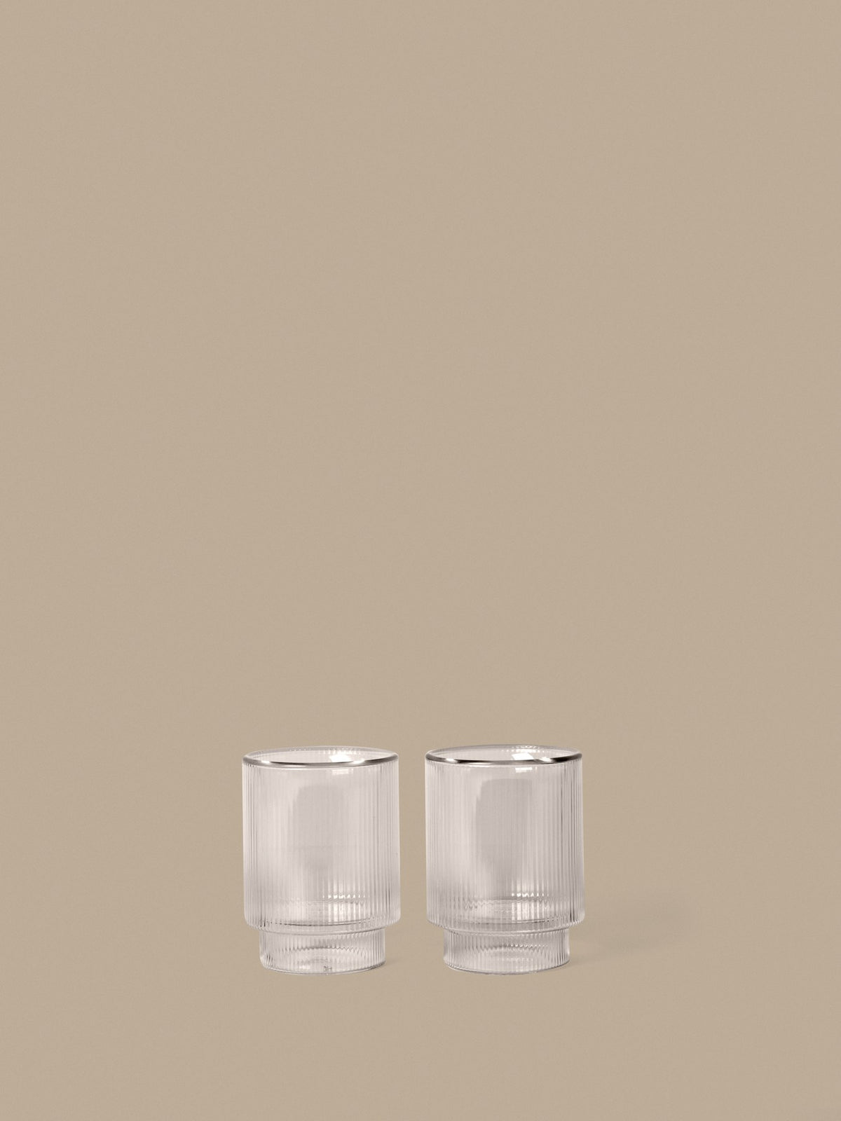 Zwei klare, doppelwandige Ripple Thermogläser von Ferm Living mit geriffelter Oberfläche aus mundgeblasenem Glas, nebeneinander auf hellem Untergrund.