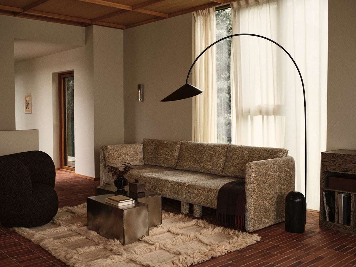 Schwarze Arum Bogenstehleuchte von Ferm Living mit massivem Marmorsockel, gebogenem Aluminium-Lampenschirm und Stoffkabel.