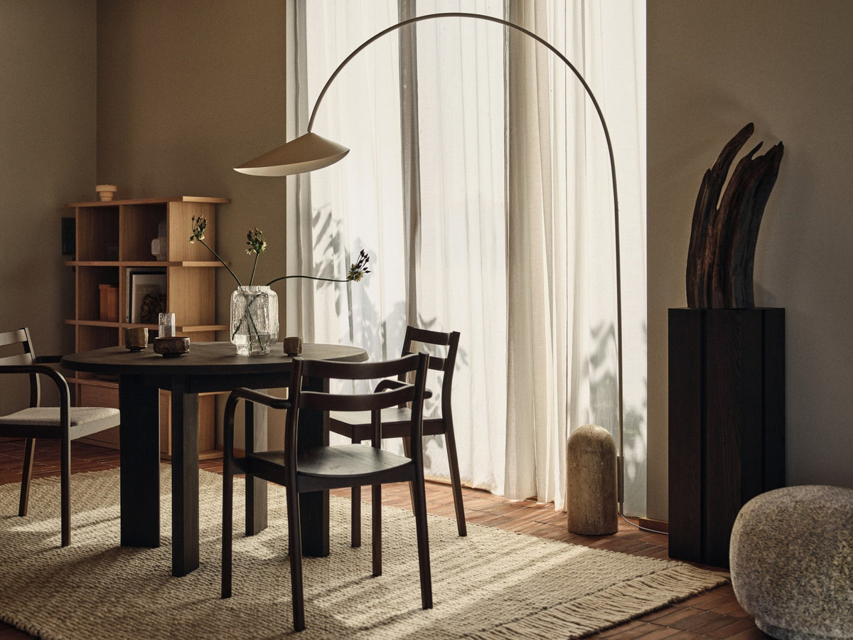 Schwarze Arum Bogenstehleuchte von Ferm Living mit massivem Marmorsockel, gebogenem Aluminium-Lampenschirm und Stoffkabel.