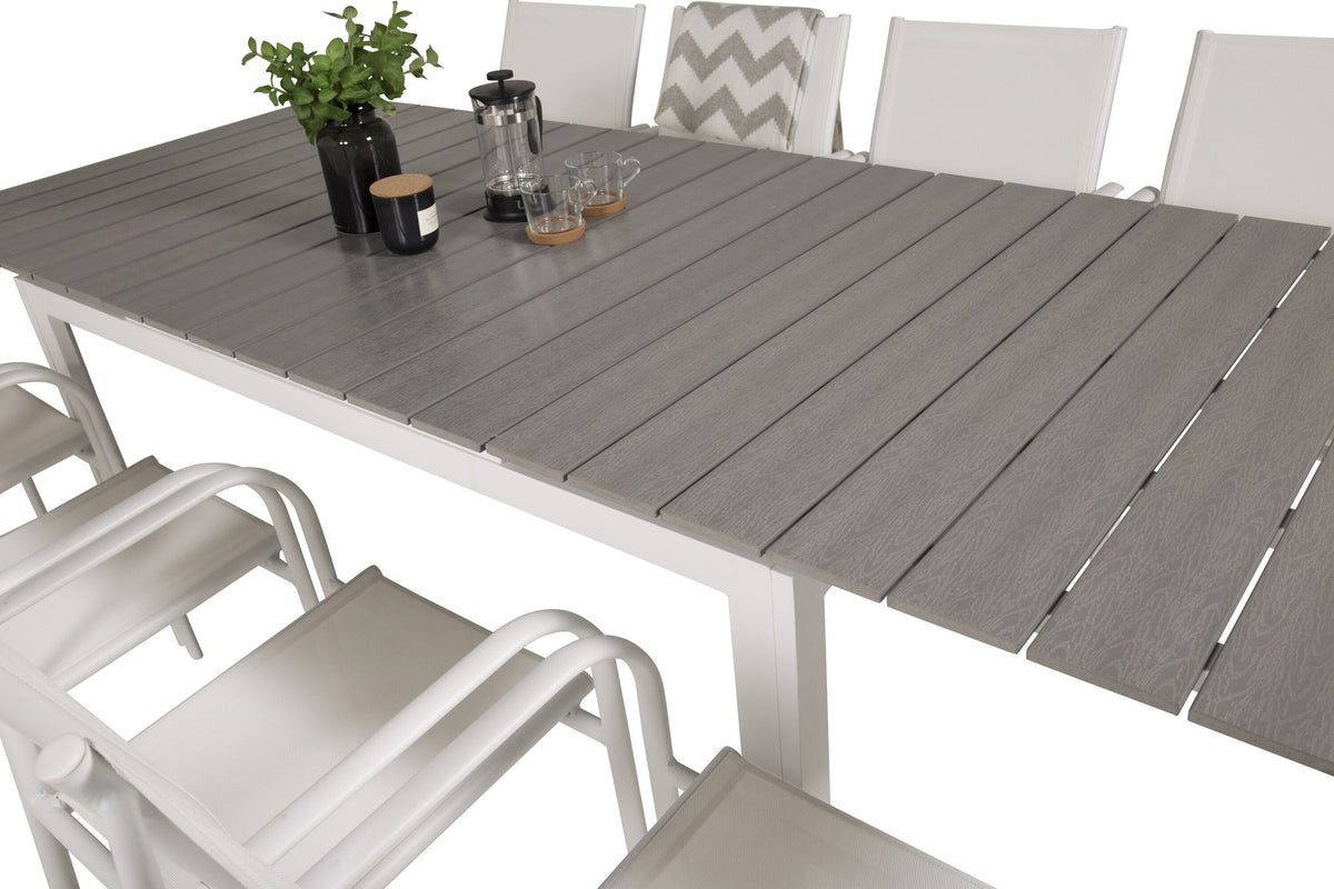 Ausziehbarer Gartentisch mit grauer Aintwood-Tischplatte und Aluminiumbeinen, umgeben von sechs weissen, stapelbaren Santorini Stühlen aus Aintwood und Aluminium.