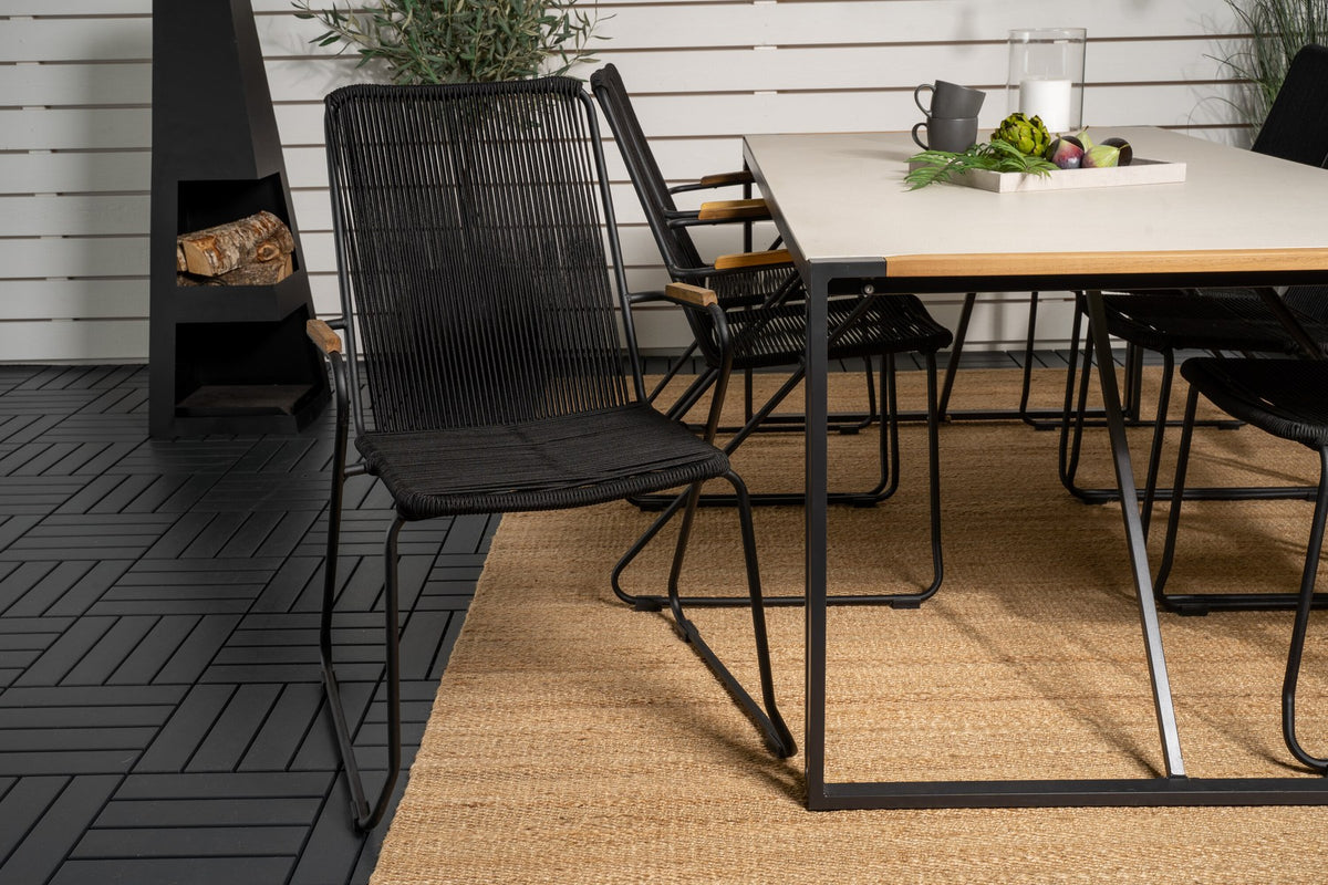 Zwei schwarze Esszimmerstühle aus Aluminium und Teakholz neben einem rechteckigen Esstisch mit Glas-Teak-Platte in Hellgrau.