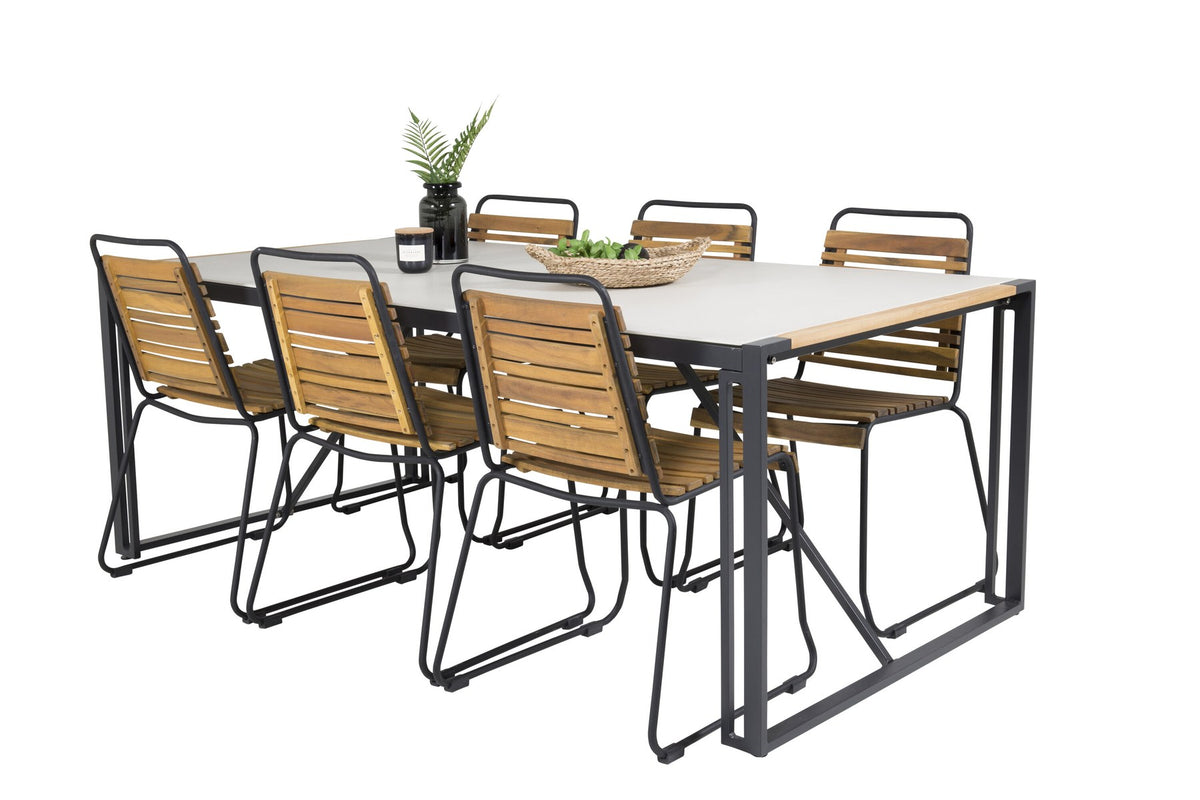 Rechteckiger Gartentisch mit schwarzer Glasplatte und Teakholz-Elementen, dazu zwei Esszimmerstühle mit Teakholz-Optik und Stahlgestell im Freien.