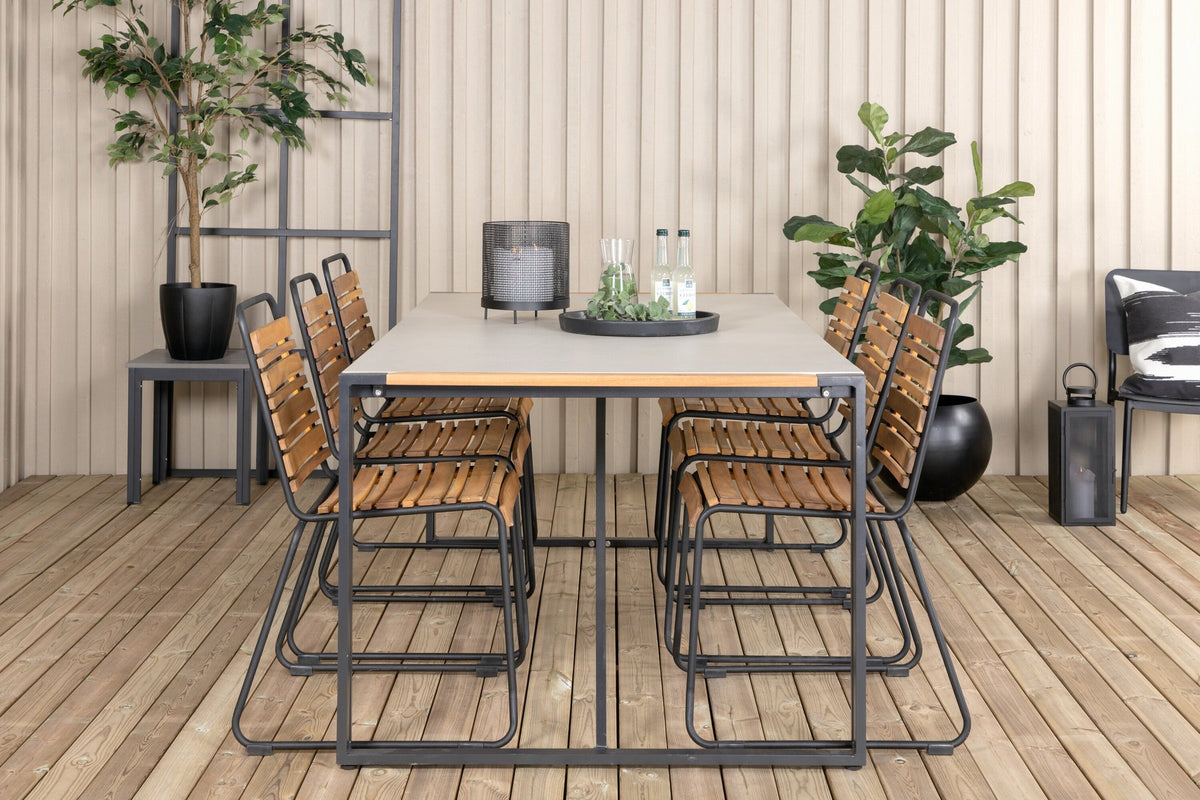 Rechteckiger Gartentisch mit schwarzer Glasplatte und Teakholz-Elementen, dazu zwei Esszimmerstühle mit Teakholz-Optik und Stahlgestell im Freien.