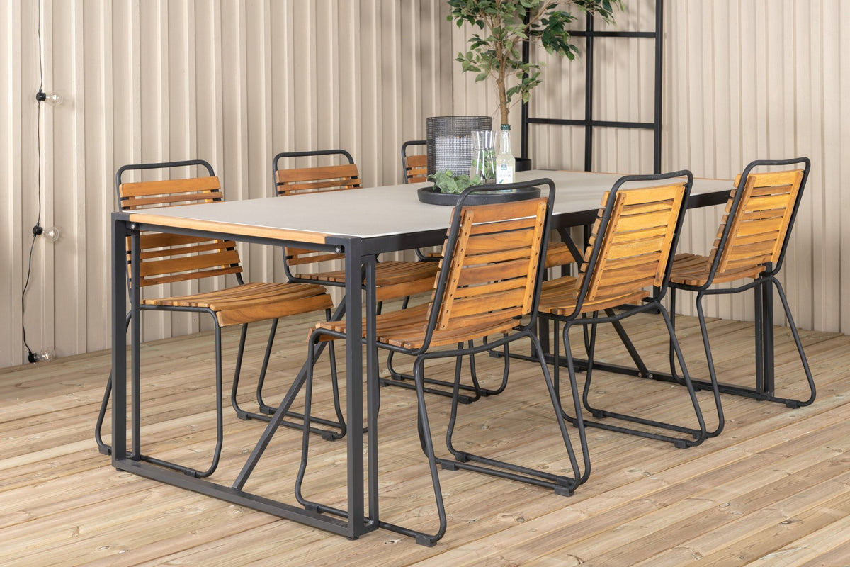 Rechteckiger Gartentisch mit schwarzer Glasplatte und Teakholz-Elementen, dazu zwei Esszimmerstühle mit Teakholz-Optik und Stahlgestell im Freien.