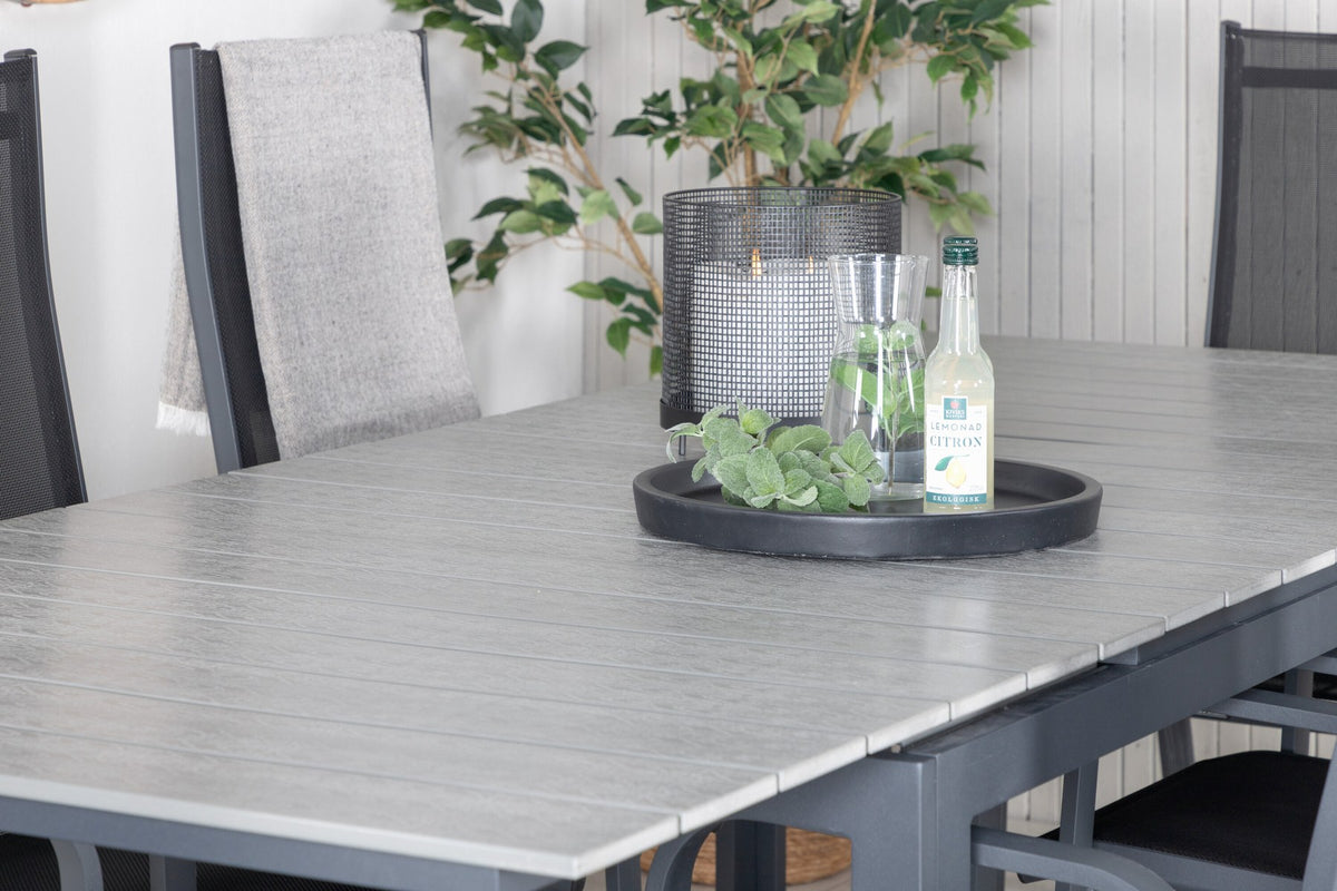 Schwarzer ausziehbarer Gartentisch Levels mit grauer Aintwood-Tischplatte und zwei stapelbaren Copacabana Sesseln aus Aluminium und Aintwood.