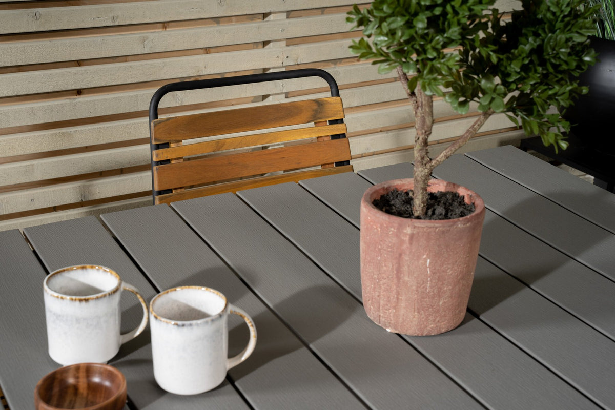 Rechteckiger Gartentisch mit grauer Aintwood-Tischplatte und schwarzem Stahlgestell, daneben zwei Esszimmerstühle aus Aintwood und Aluminium in Natur.